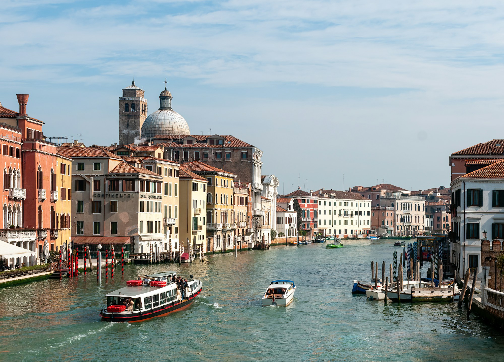 Boats moored on a Venice canal, with the Grand Canal in the background