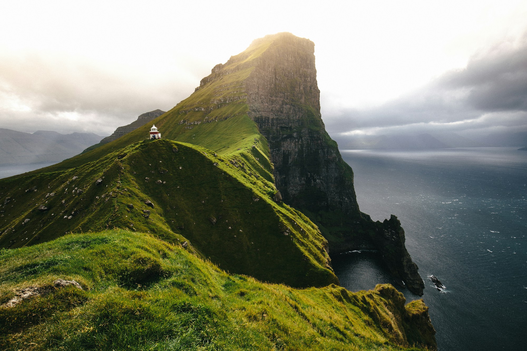 Village with grass-roof houses in the Faroe Islands facing cliffs and Atlantic Ocean