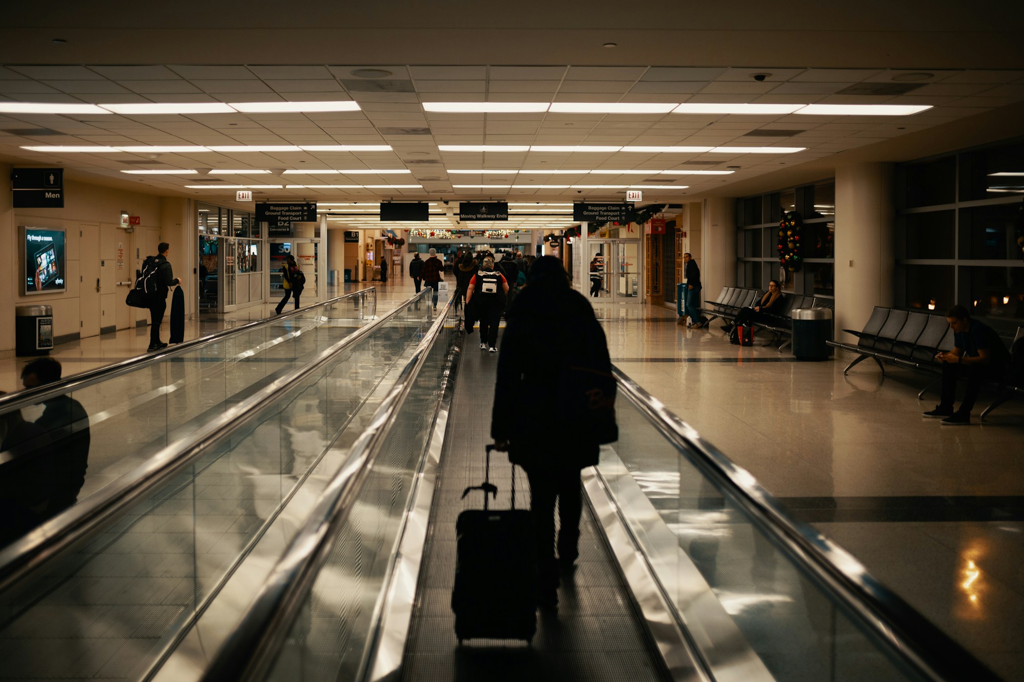 Voyageur marchant dans un aéroport avec une valise à roulettes