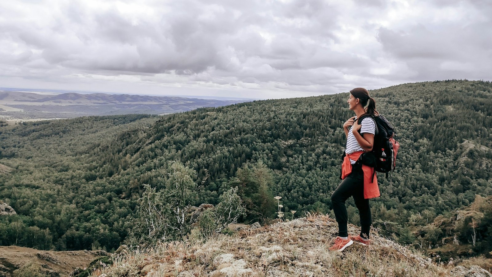 Randonneuse avec sac à dos contemplant un panorama montagneux, trek en pleine nature