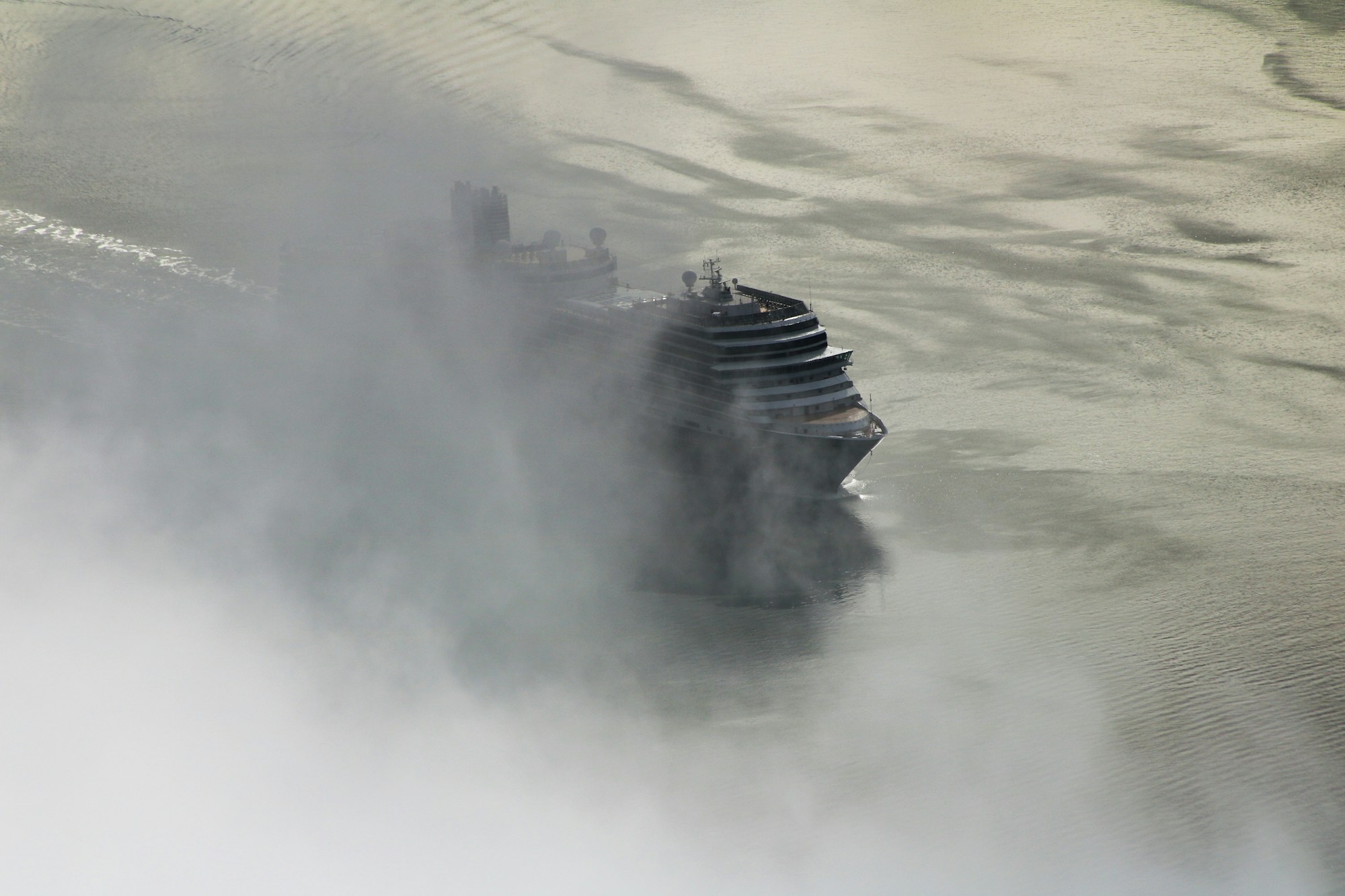 Cruise ship sailing through the fjords of Alaska surrounded by mist