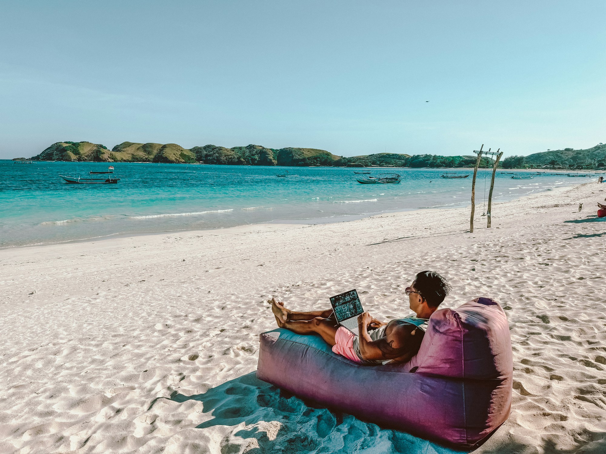 Digital nomad travaillant sur son laptop sur une plage à Lombok