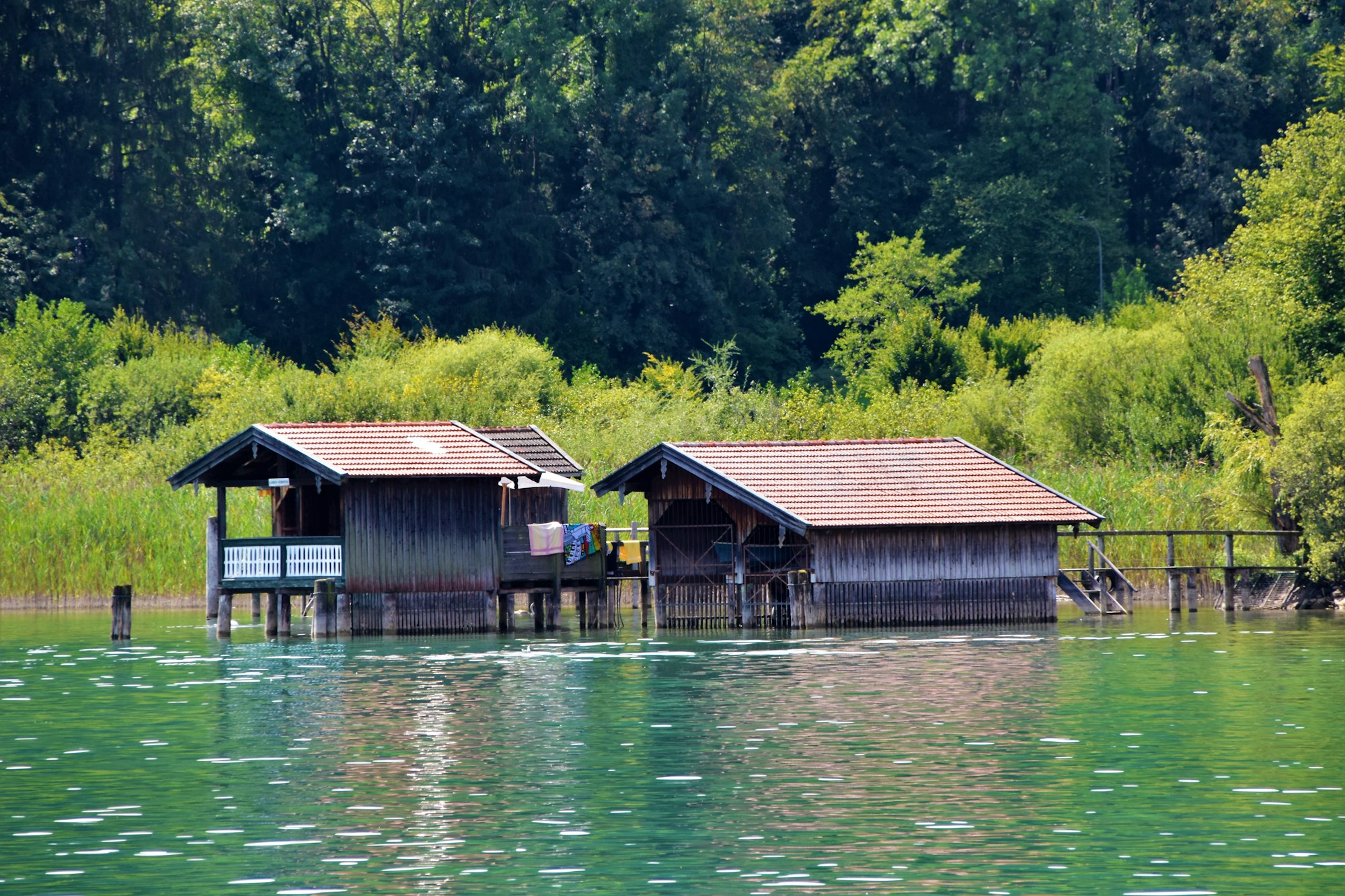 Two wooden chalets on the edge of a tranquil lake surrounded by forest