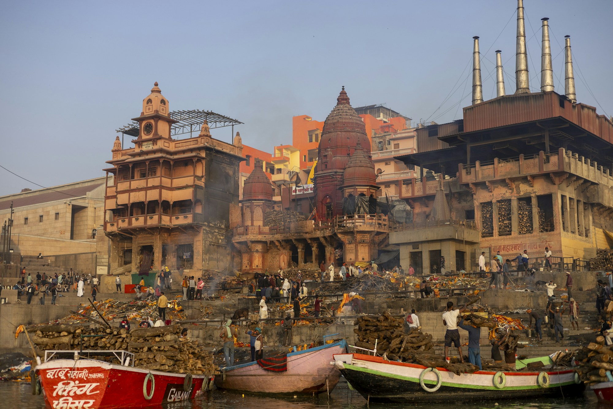 Bateaux flottant sur le Gange à Varanasi au lever du soleil, avec les ghats et les temples en arrière-plan