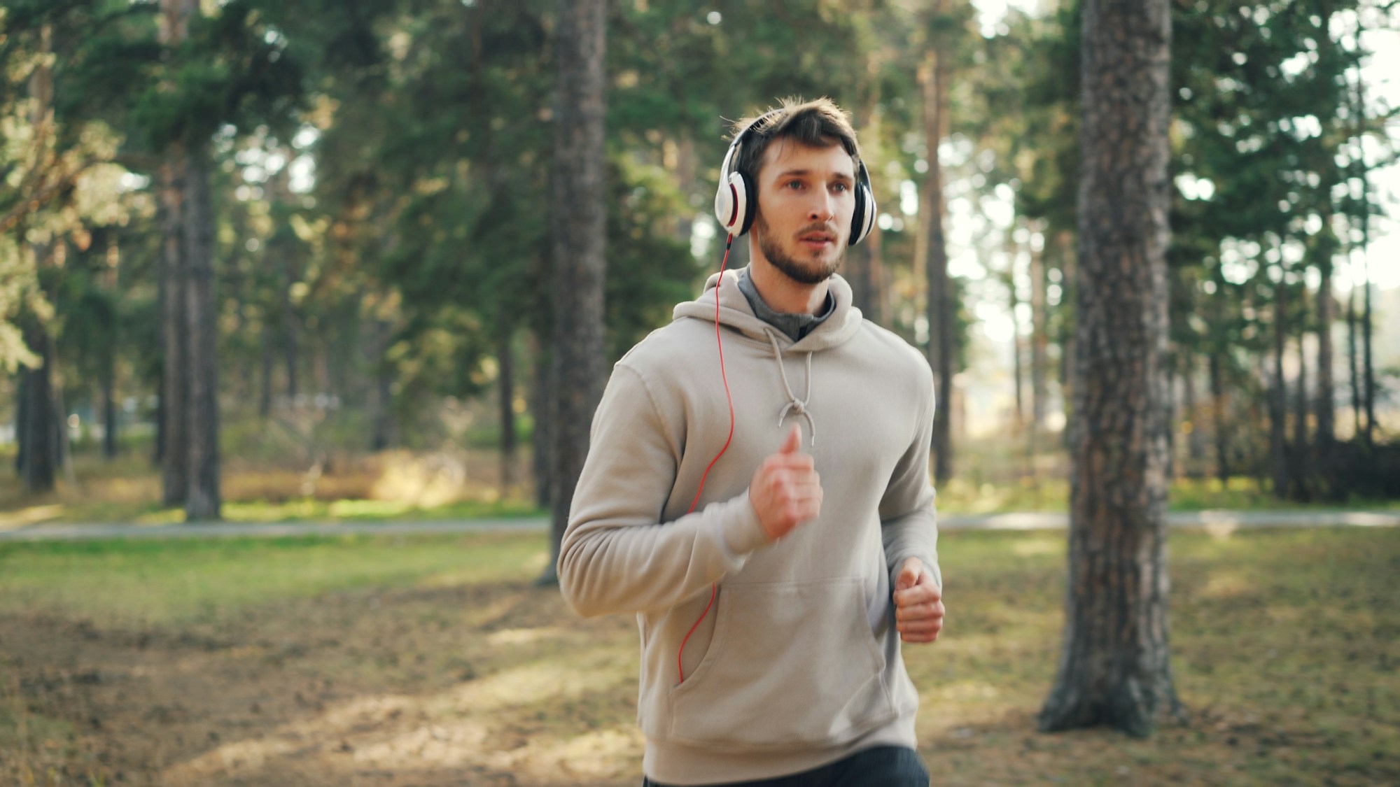 Mann joggt mit Kopfhörern im Wald, als Illustration von Bewegung im Freien gegen Jetlag