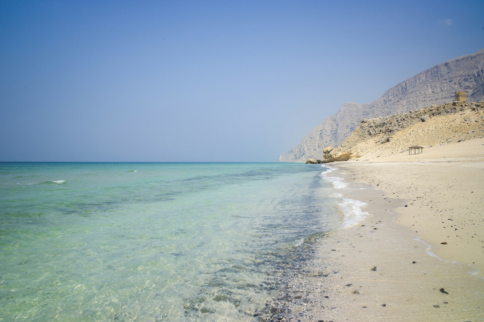 Plage isolée entourée de falaises dans la péninsule de Musandam, Oman