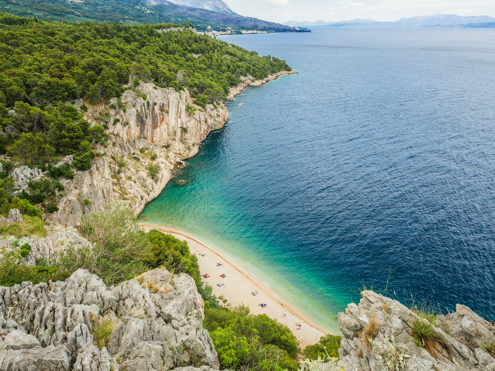 Aerial view of Pasjača Beach, a narrow strip of golden sand beneath cliffs in Southern Dalmatia, Croatia