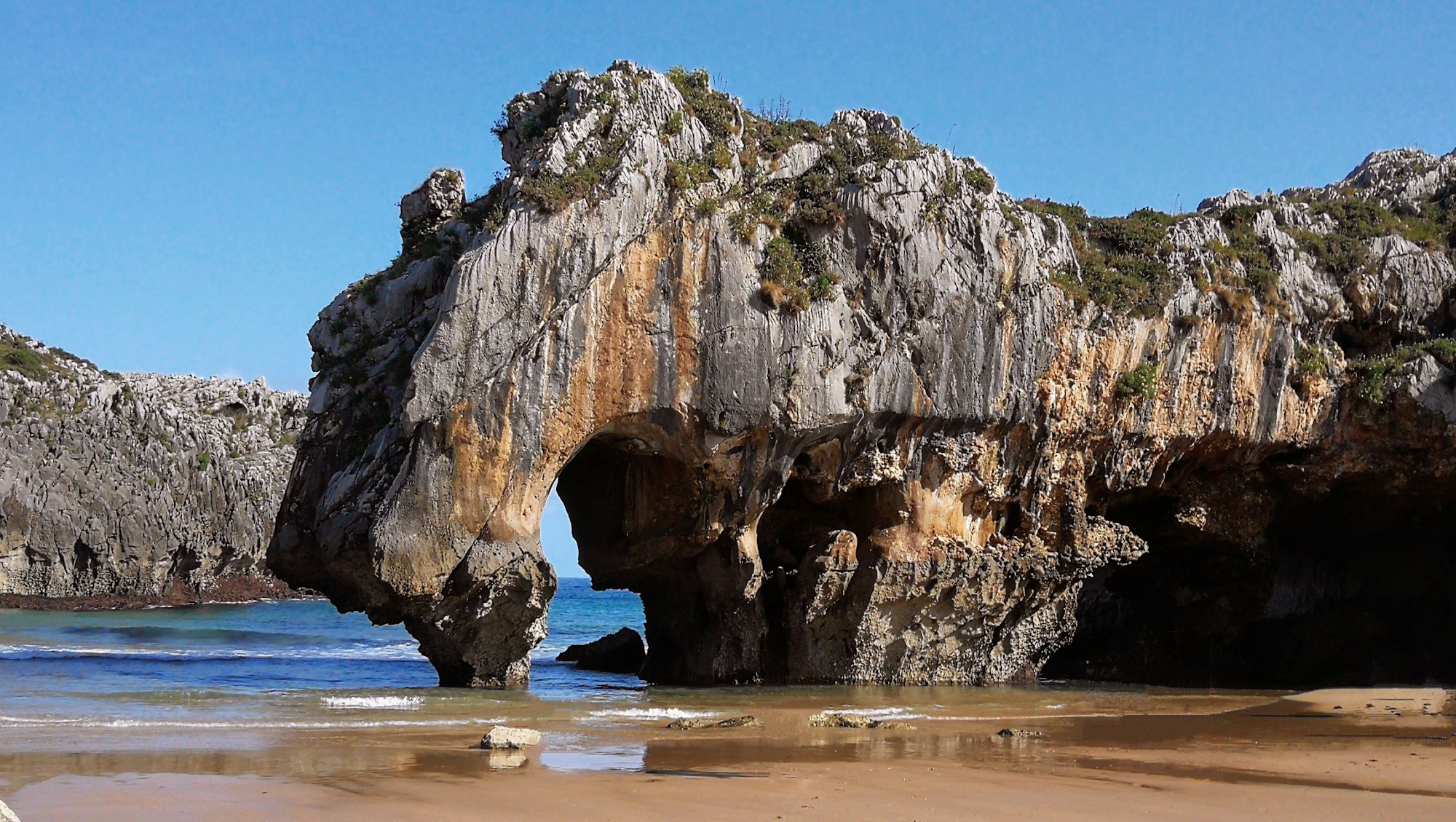 Playa del Moraig framed by imposing cliffs with its swim-through sea cave on the Costa Blanca, Spain