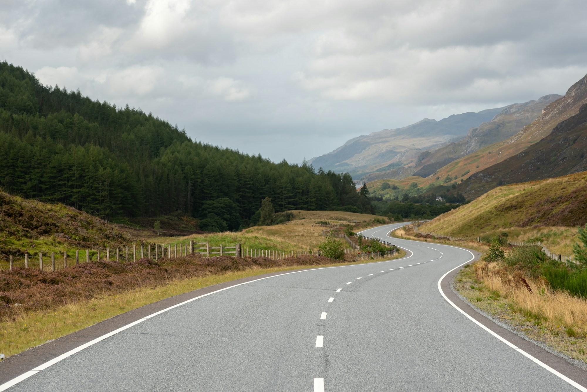 Route sinueuse dans les Highlands écossaises avec montagnes enneigées