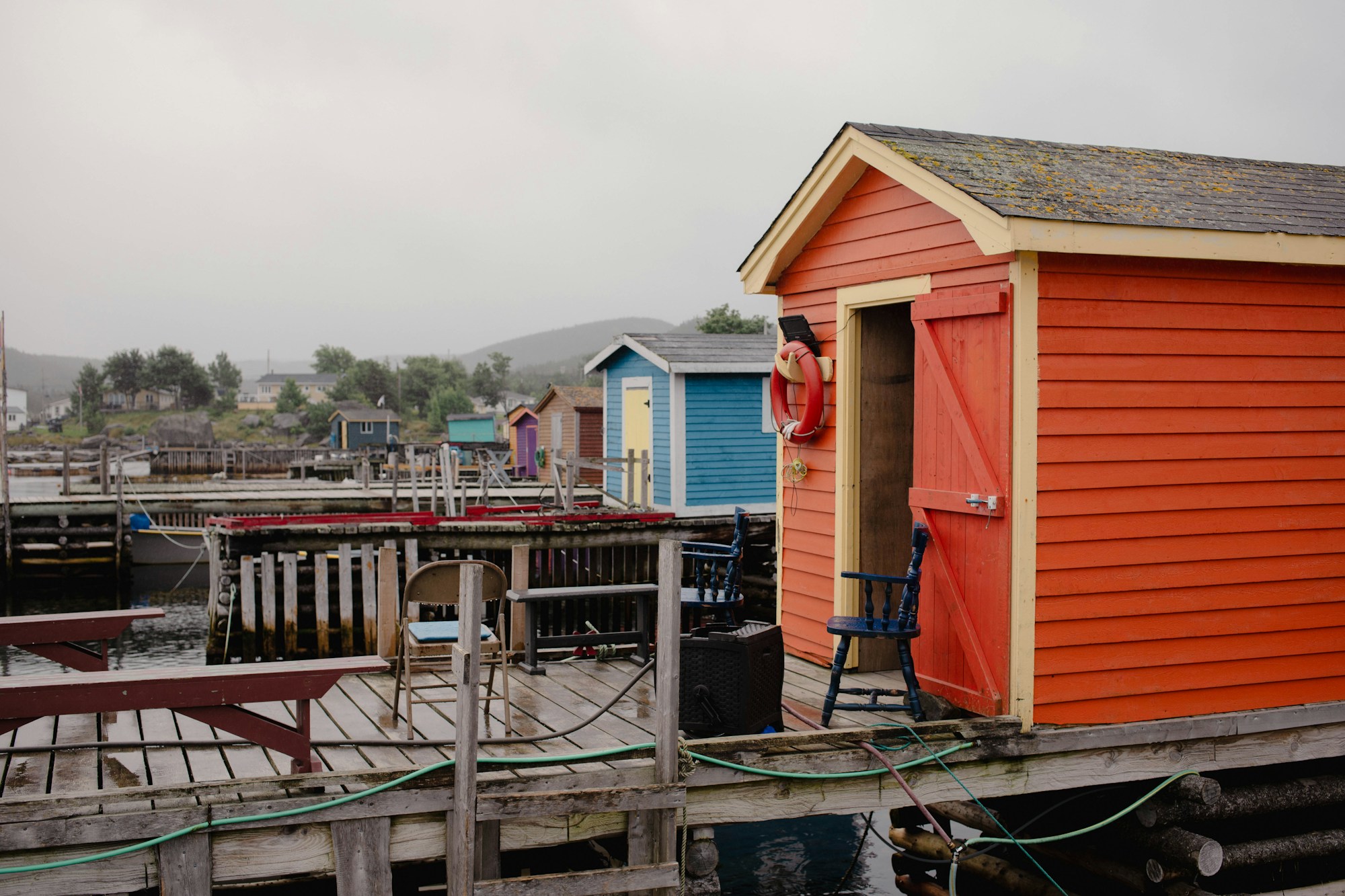 Dock de pêche en bois avec un bâtiment rouge et jaune sur la côte de Terre-Neuve, Canada, reflets dans l'eau calme