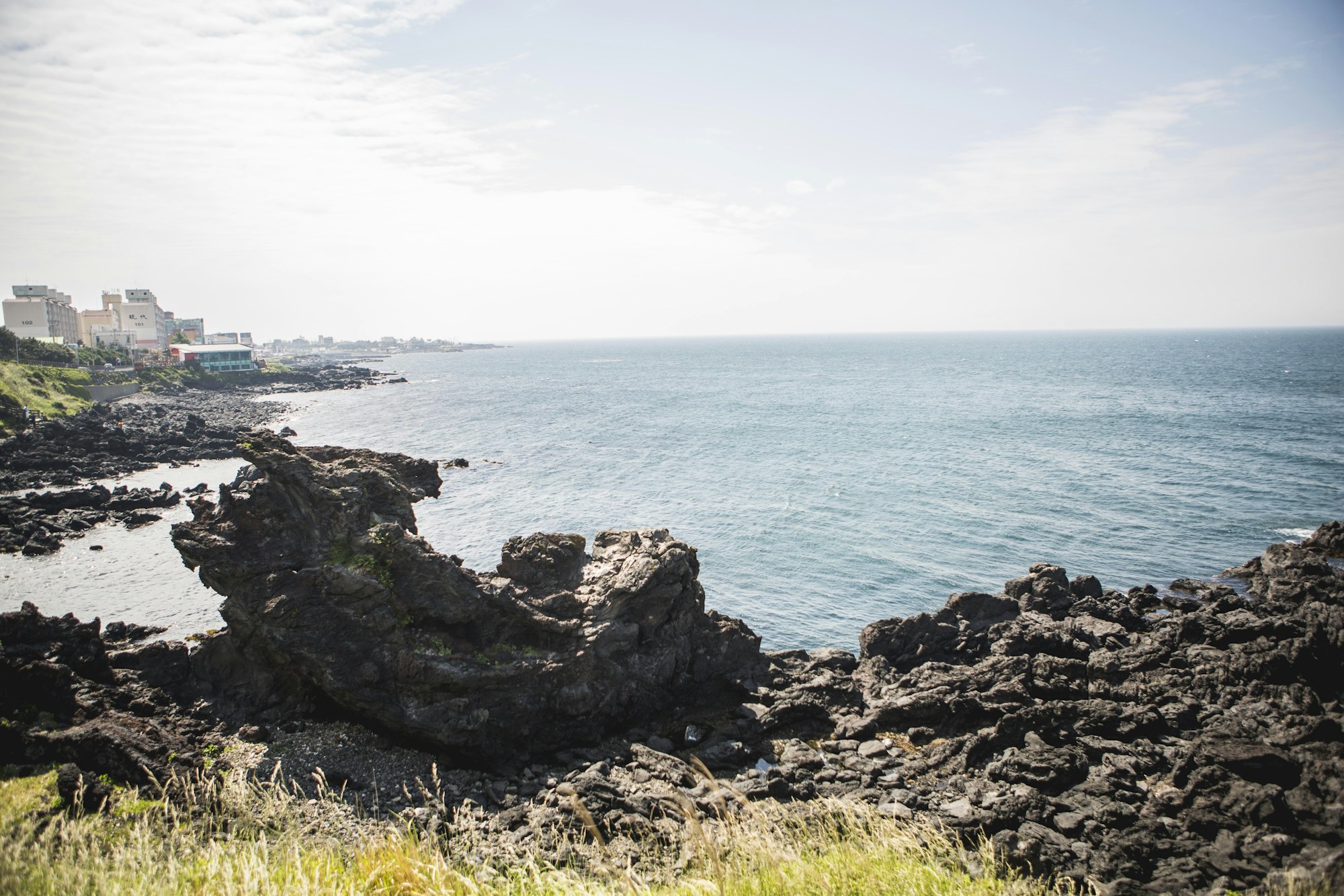 Volcanic landscape of Jeju Island in South Korea, with green hills plunging into the blue sea