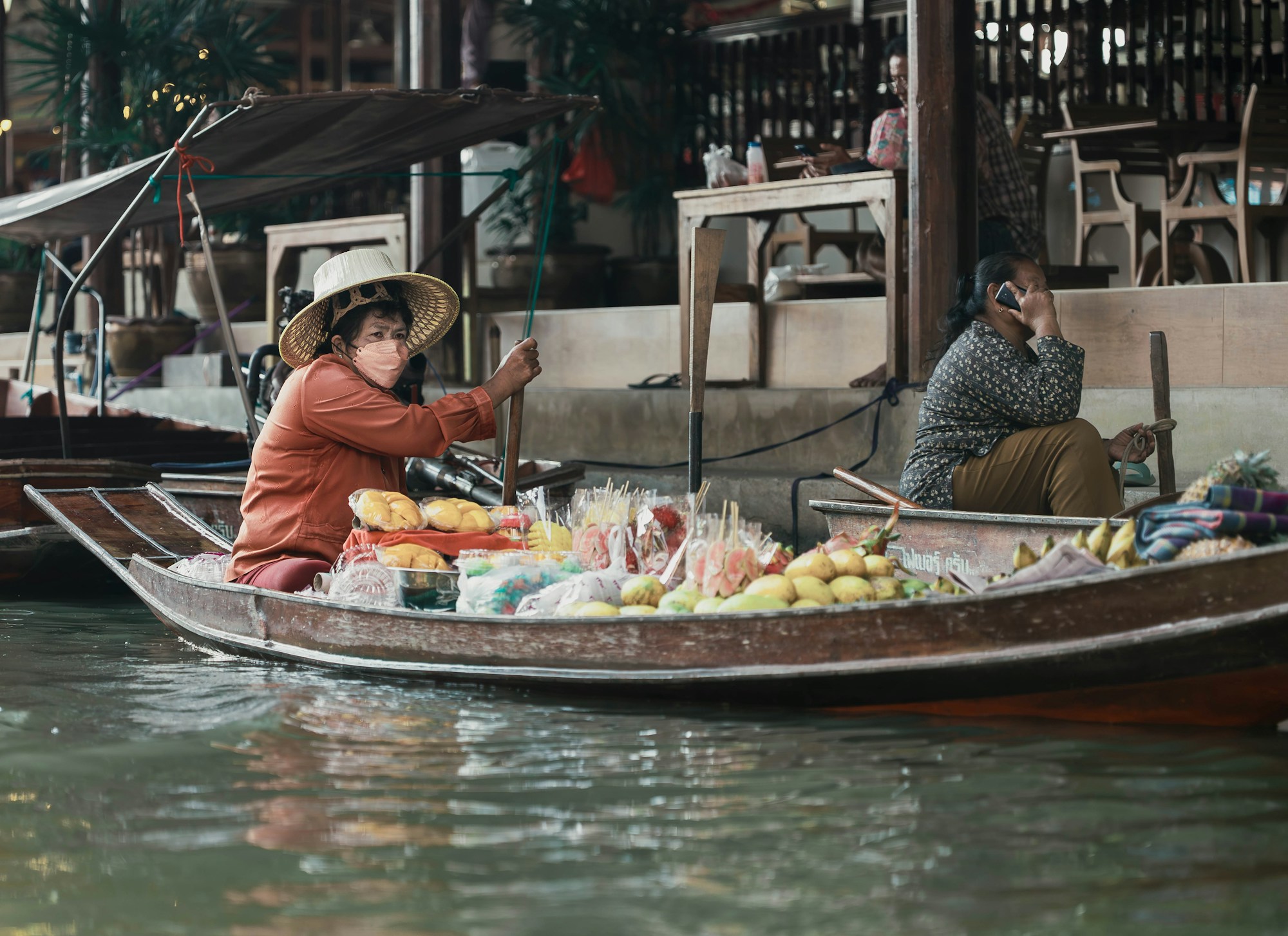 Vendeuse thaïlandaise sur une barque chargée de fruits tropicaux dans un marché flottant