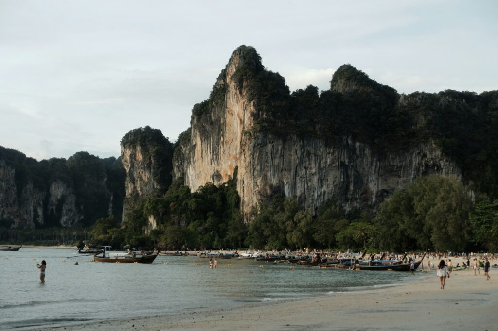 Plage de Railay à Krabi avec falaises calcaires et bateaux longtail dans les eaux turquoise de la côte Andaman en Thaïlande