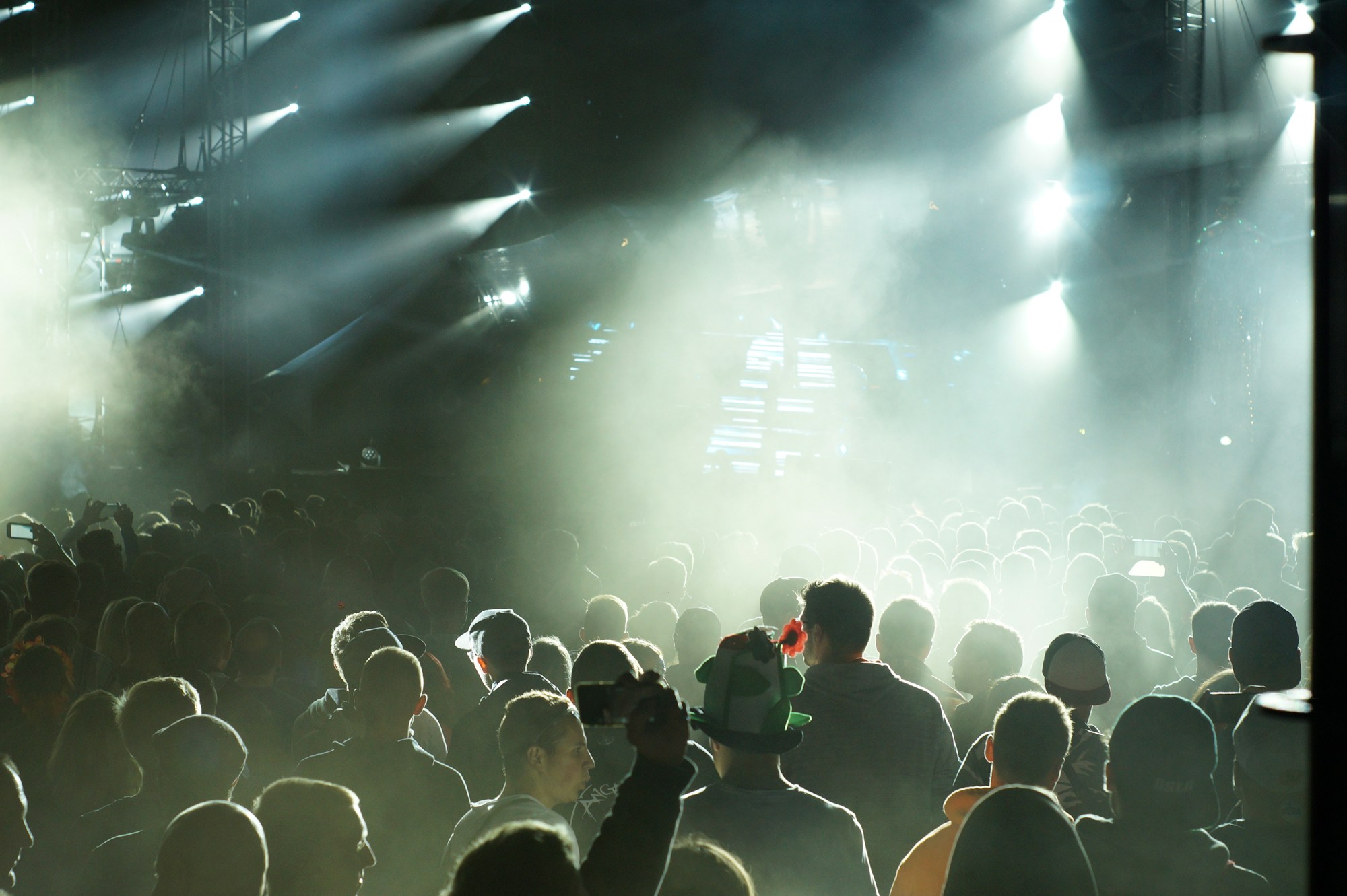 Scène principale d'un grand festival de musique électronique avec jeux de lumières spectaculaires et foule de festivaliers