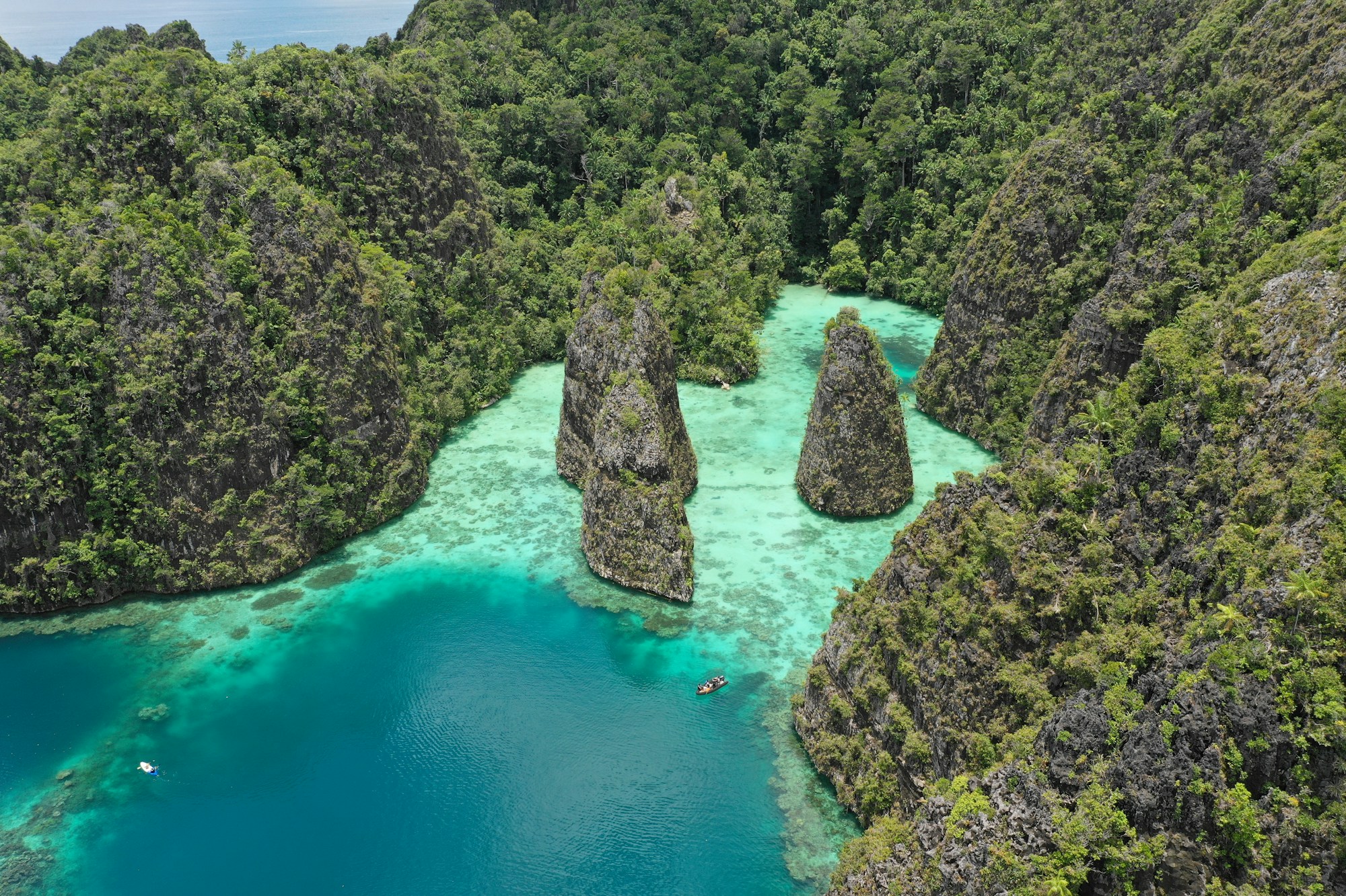Luftaufnahme der tuerkisfarbenen Lagune von Raja Ampat, Indonesien, umgeben von tropischem Regenwald