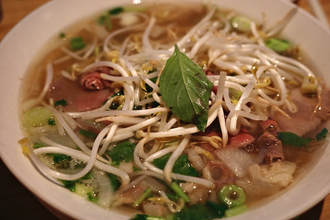 Traditional bowl of pho bo with fresh herbs and chopsticks in Vietnam