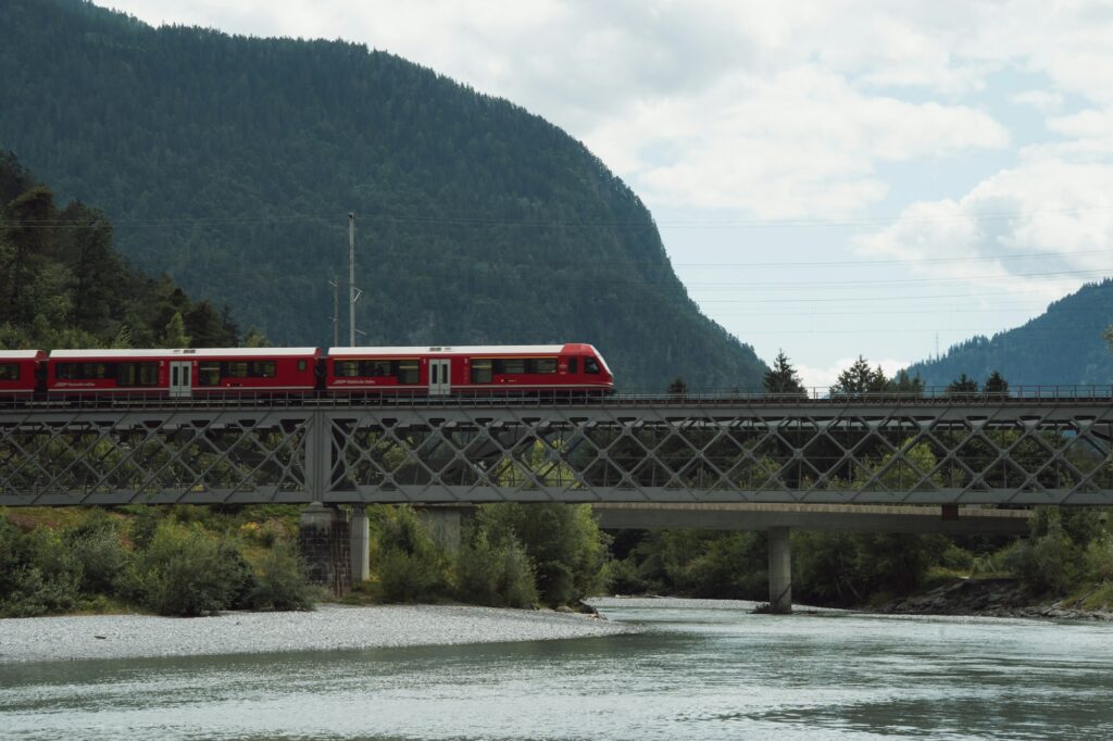 Train rouge traversant un viaduc dans les Alpes suisses - Ligne European Sleeper Bruxelles-Milan