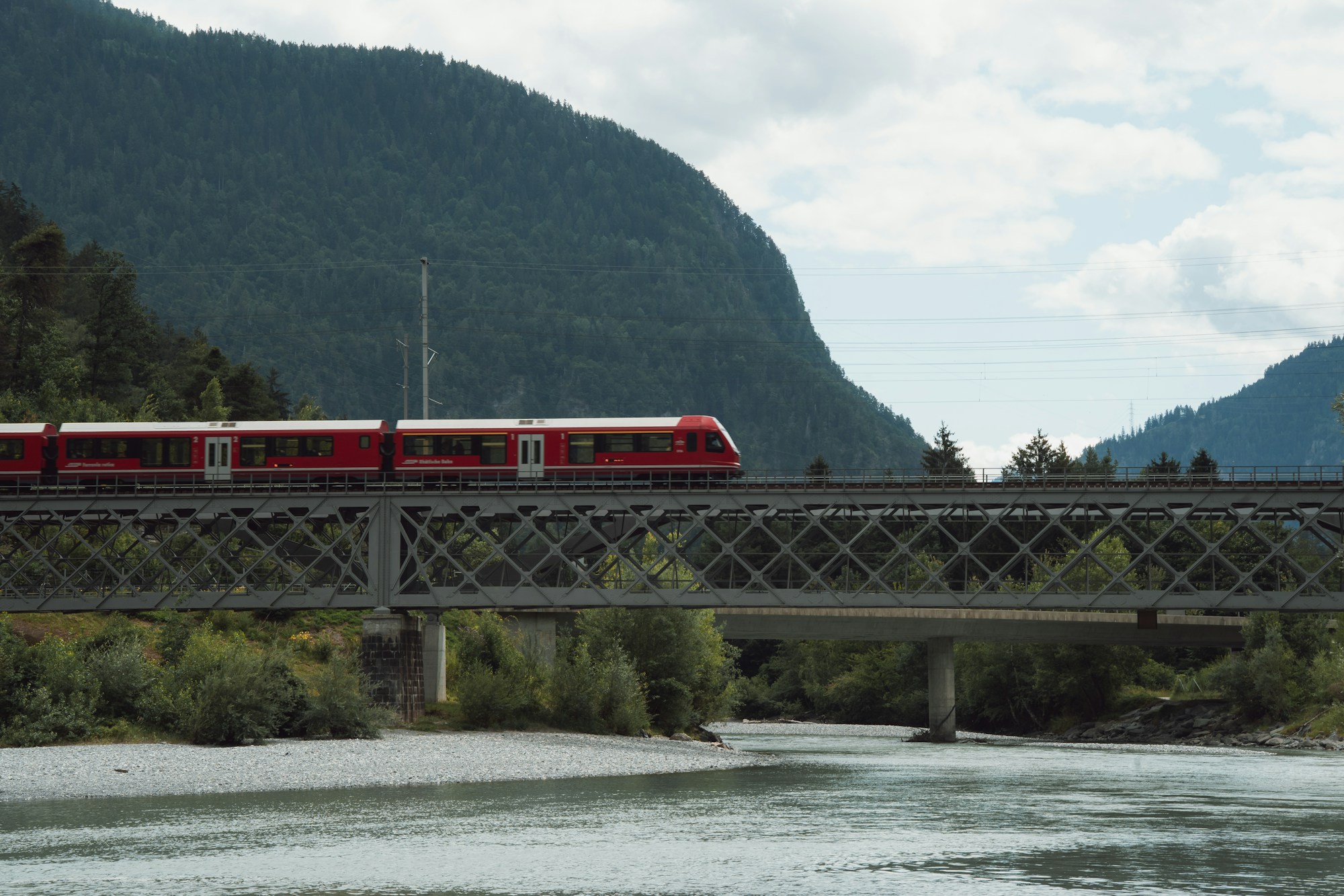 Treno rosso che attraversa un viadotto nelle Alpi svizzere - Linea European Sleeper Bruxelles-Milano