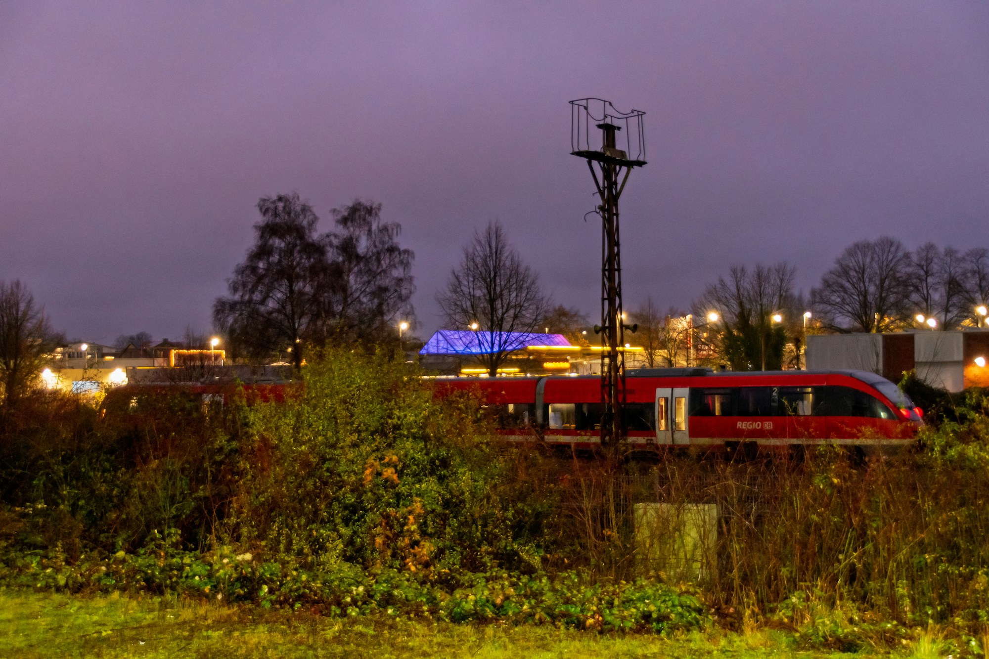 Train rouge traversant un paysage rural européen au crépuscule