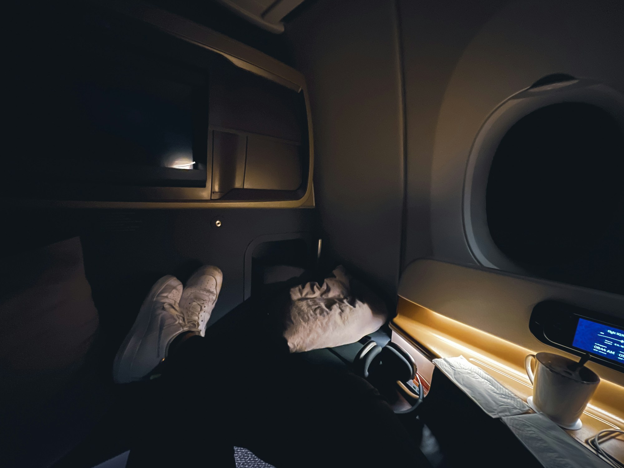 Passenger sleeping on an airplane with a neck pillow and sleep mask