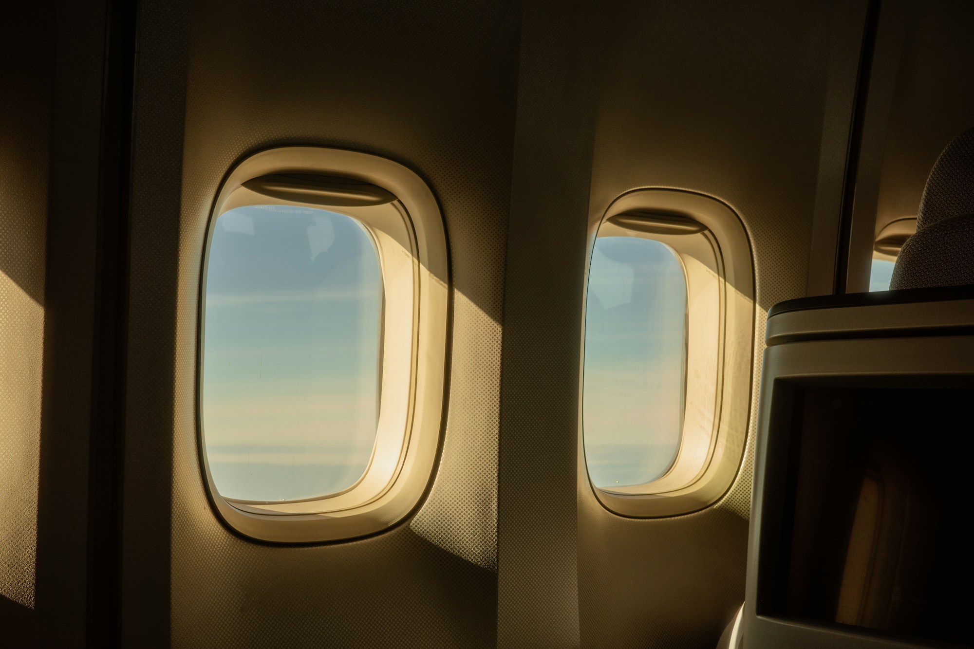 Sonnenlicht durch Flugzeugfenster über den Wolken — optimales Buchungstiming