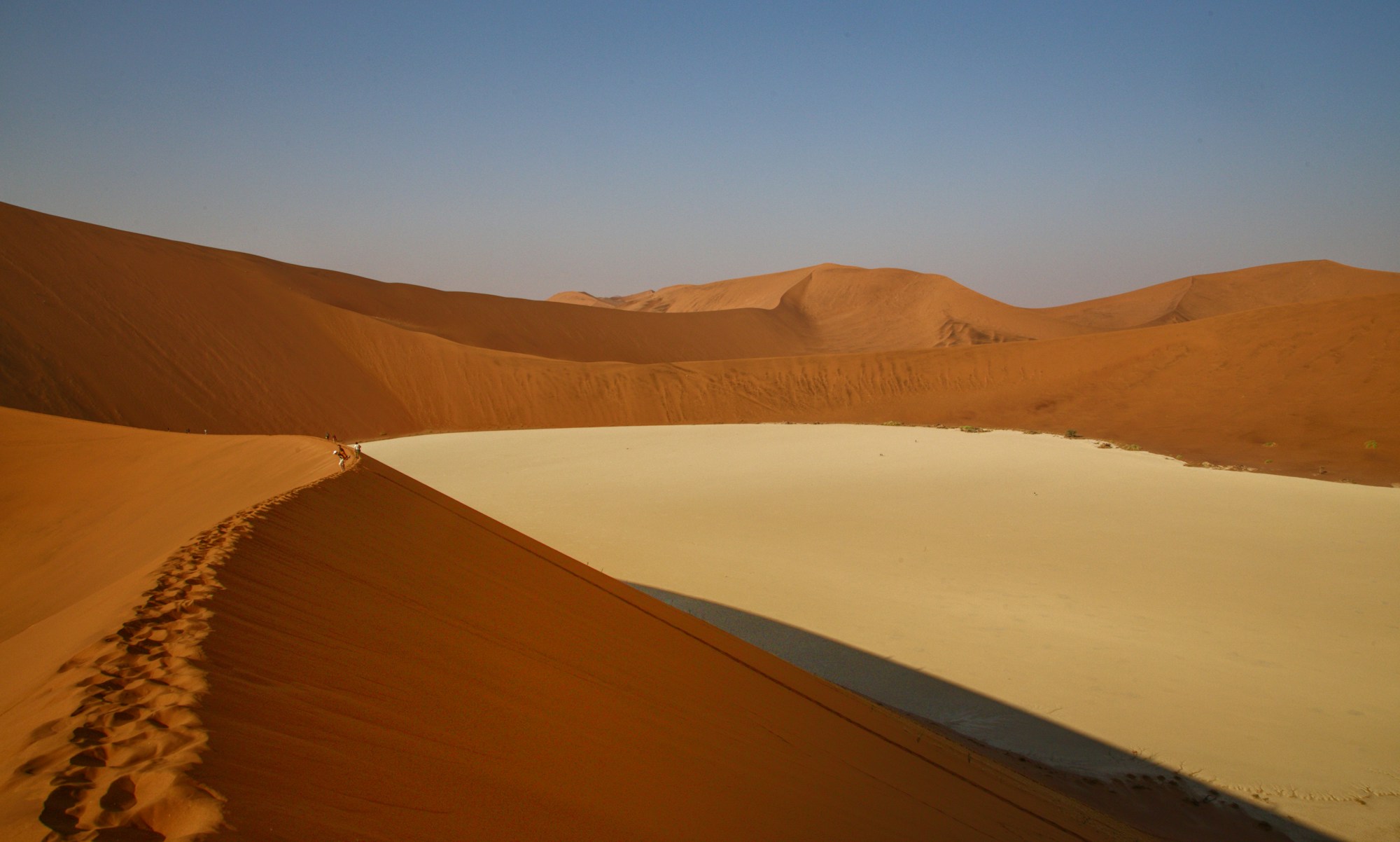 Vue depuis la Grande Dune sur le Deadvlei, arbres morts et sol blanc entourés de dunes orangées à Sossusvlei, Namibie