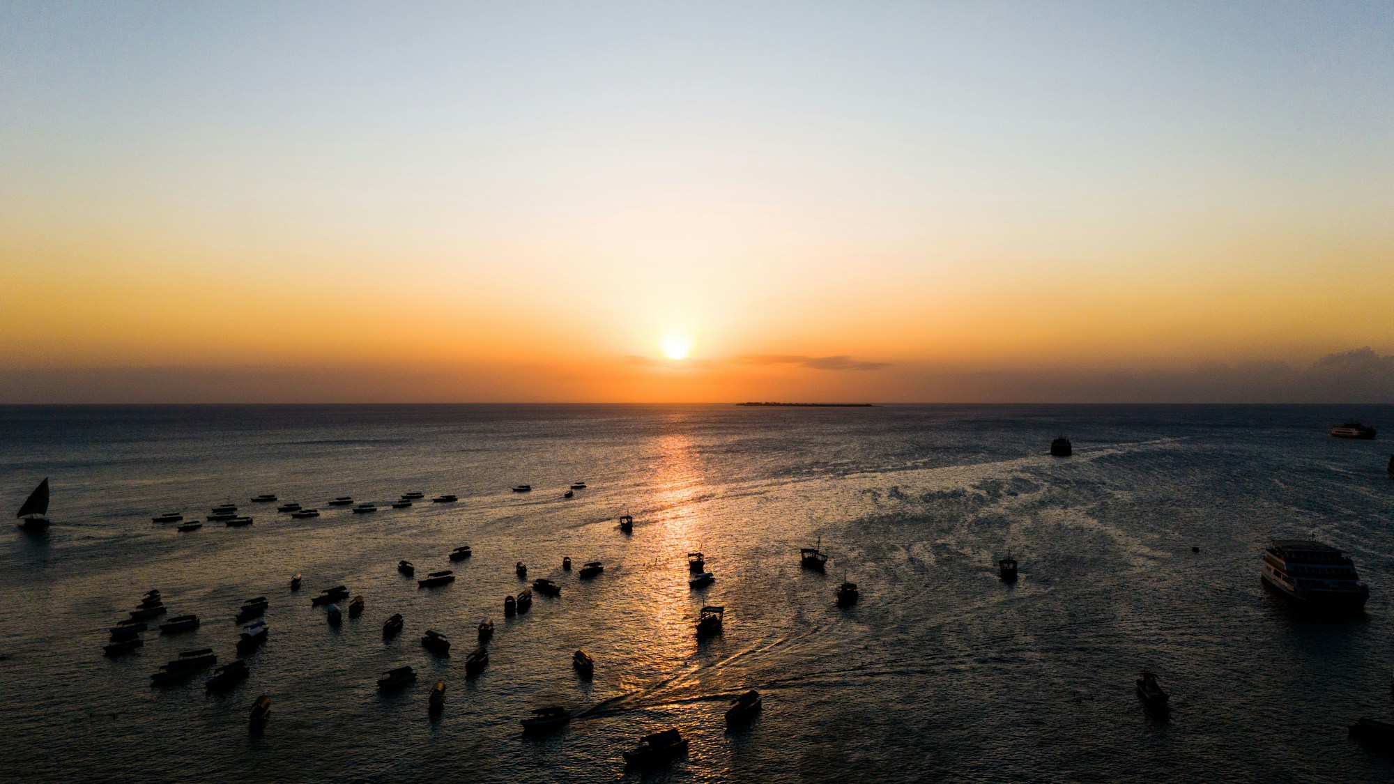 Coucher de soleil sur Stone Town à Zanzibar avec dhows traditionnels sur l'océan Indien