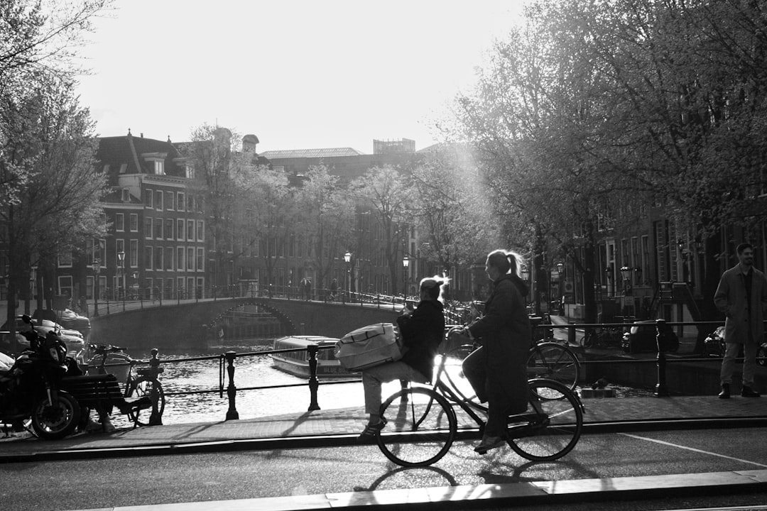 Cycliste longeant un canal d'Amsterdam bordé de tulipes en fleurs au printemps