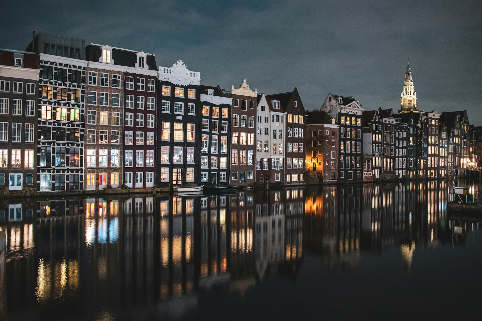 Canaux d'Amsterdam illuminés en soirée, reflets des lampadaires sur l'eau, bateaux amarrés