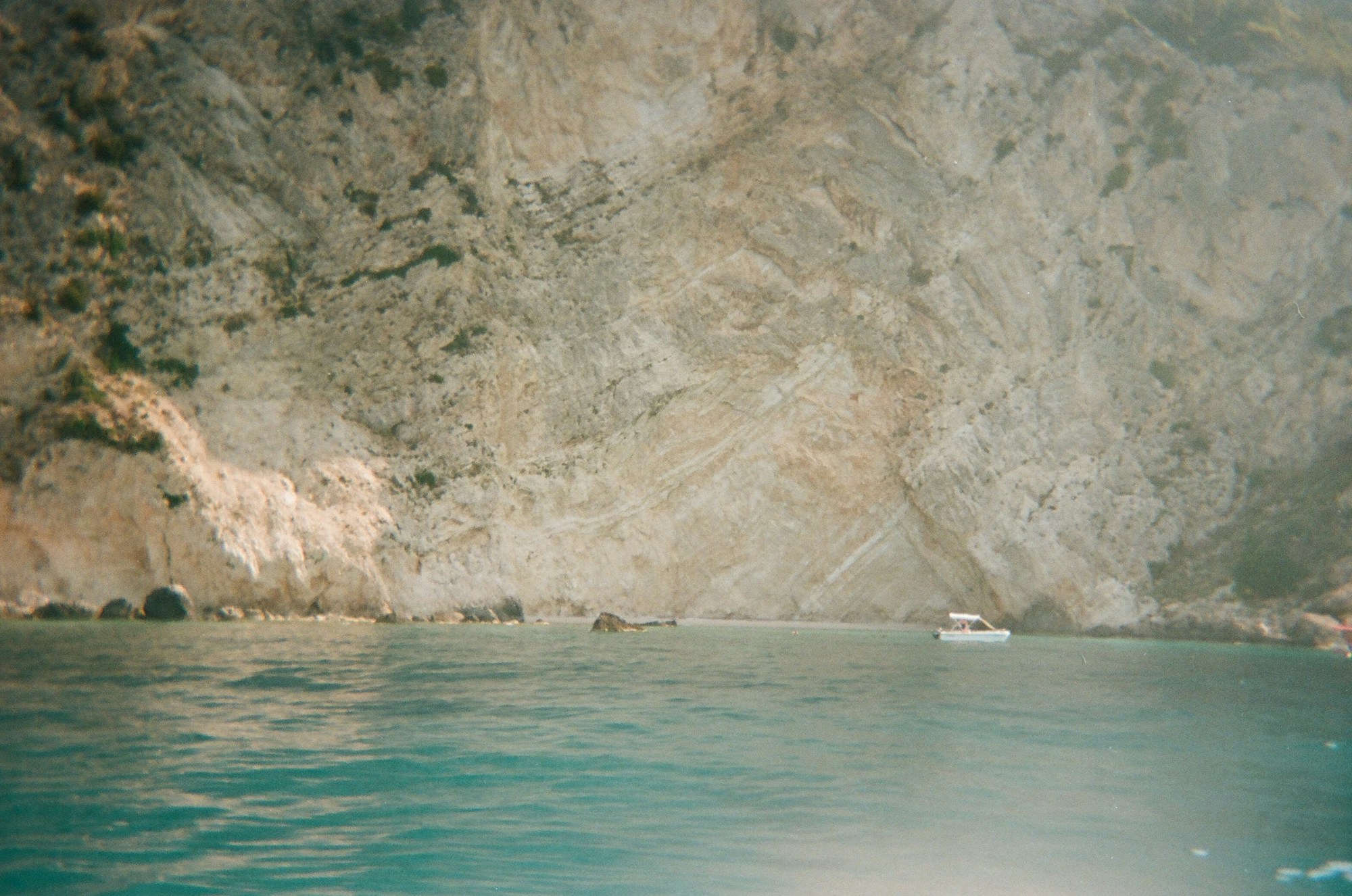 Bateau près d'une falaise rocheuse sur la côte corse, eaux turquoise