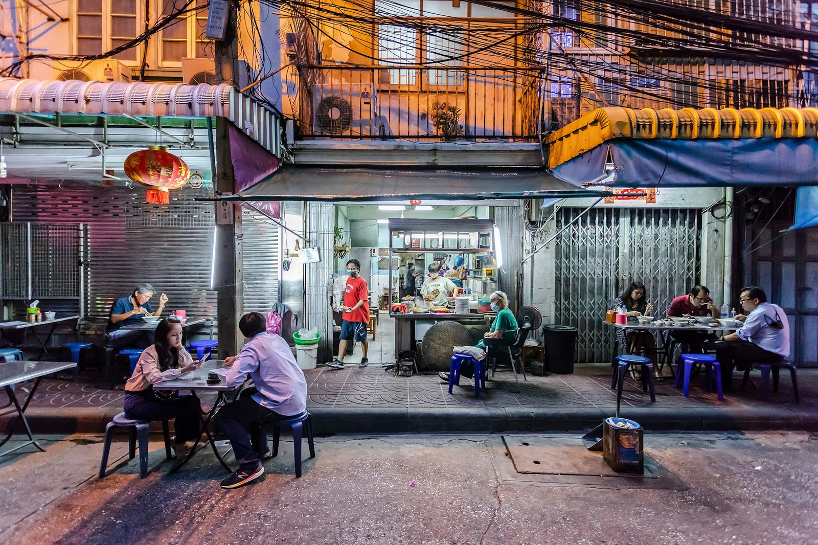Illuminated street food stalls at night in a Bangkok shophouse
