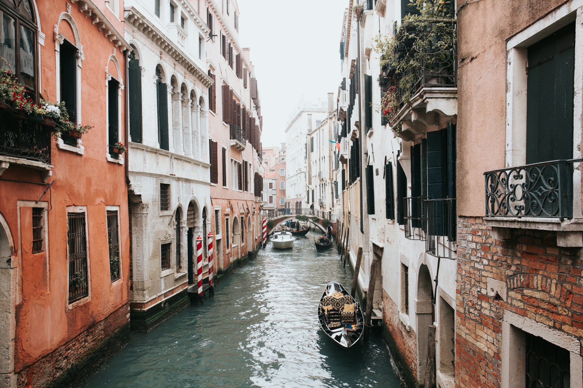 Canal veneciano con reflejos dorados en el agua, edificios históricos al fondo