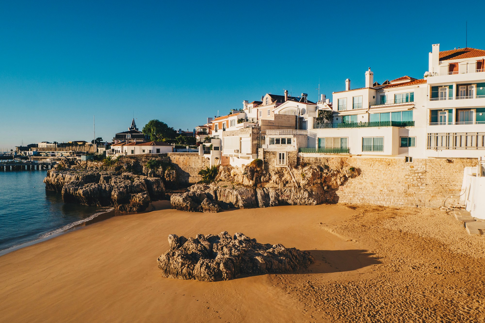 La plage de Cascais baignée de soleil avec ses eaux bleu atlantique et ses visiteurs profitant du sable doré