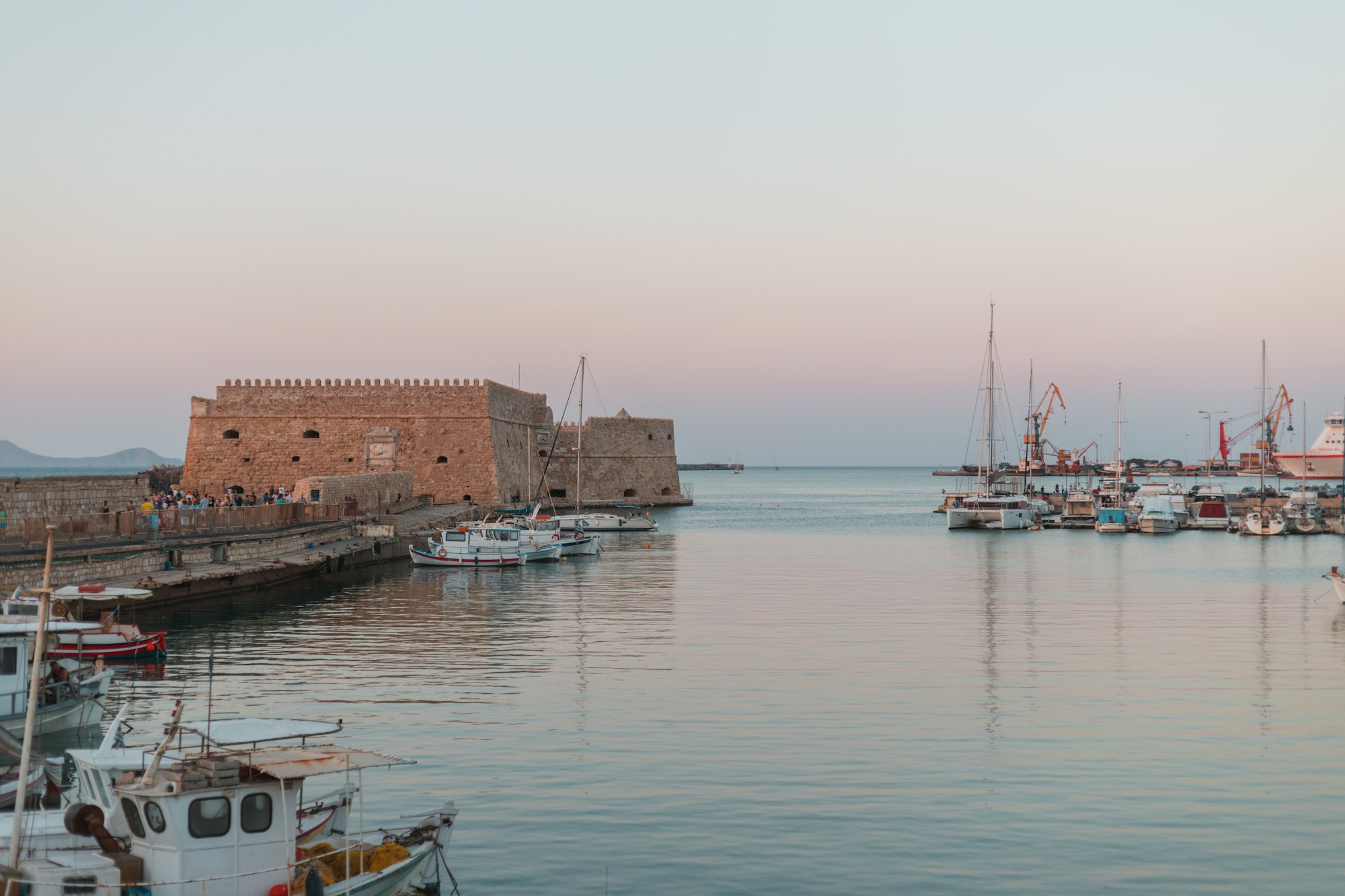Port d'Héraklion en Crète avec bateaux de pêche colorés et forteresse vénitienne en arrière-plan