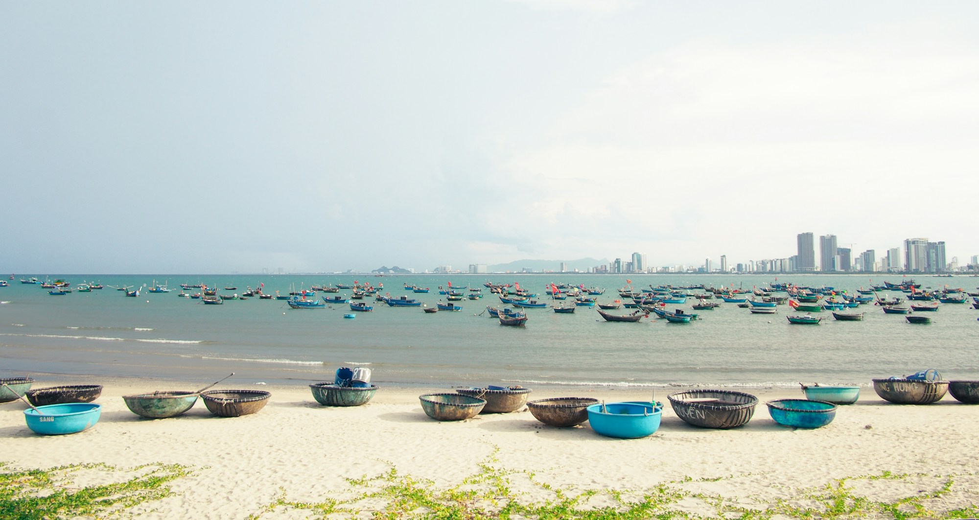 Plage de Da Nang avec bateaux de pêche colorés et skyline en arrière-plan, Vietnam