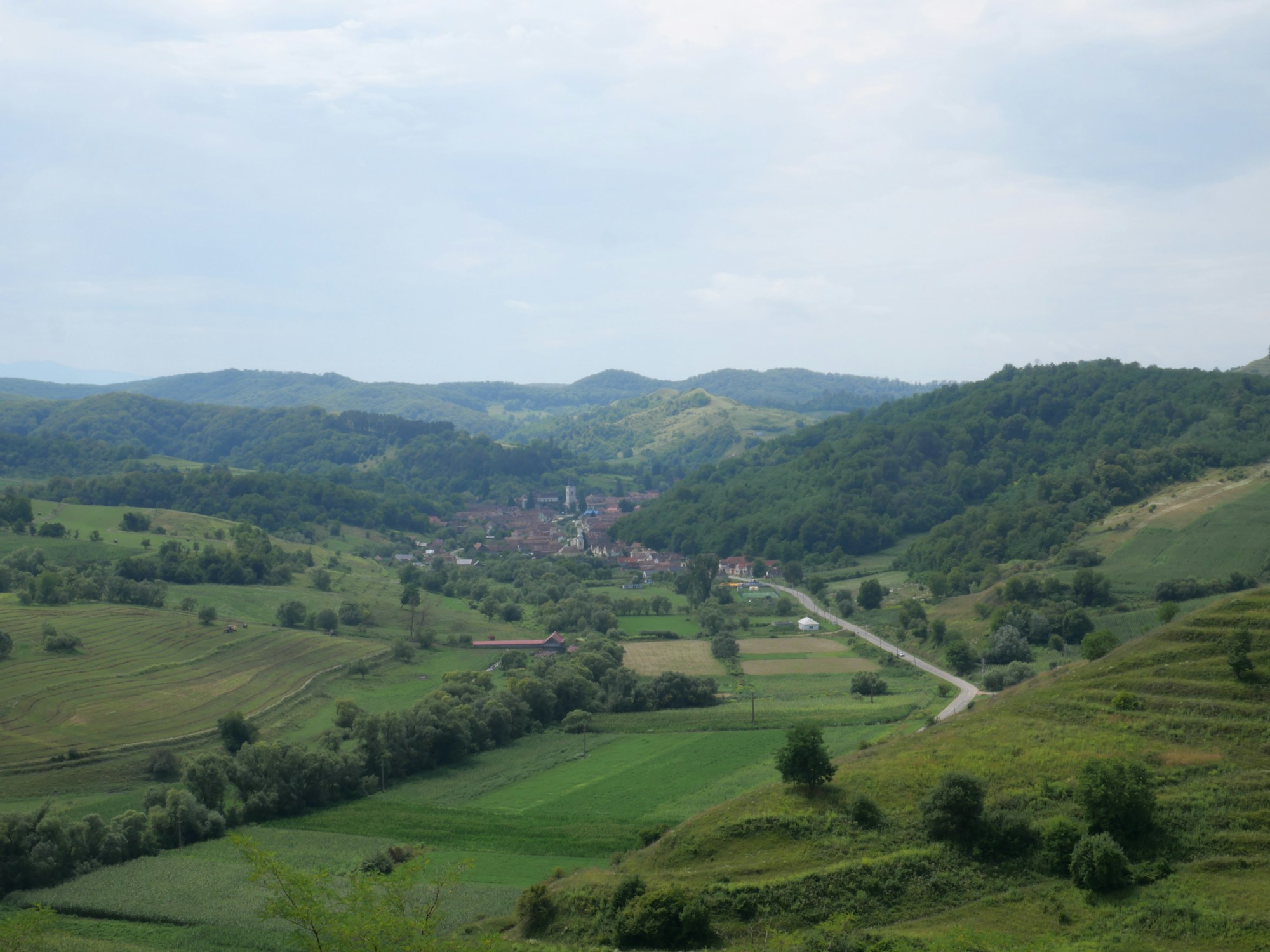 Paysage rural en Roumanie, collines vertes et village niché dans la vallée — cadre du festival Electric Castle