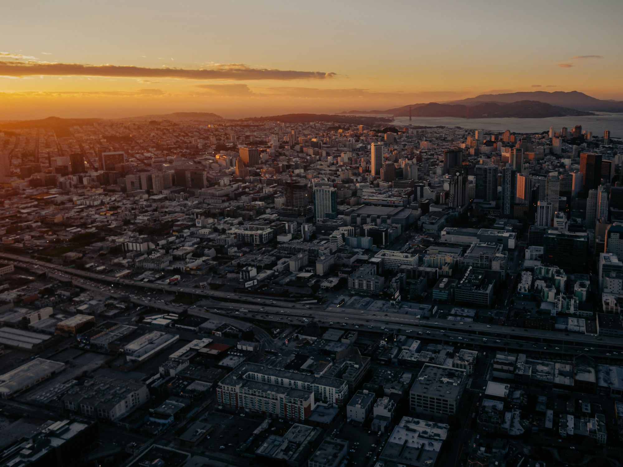 Vista aérea de una metrópolis moderna al atardecer — el futuro escenario de los taxis aéreos eléctricos