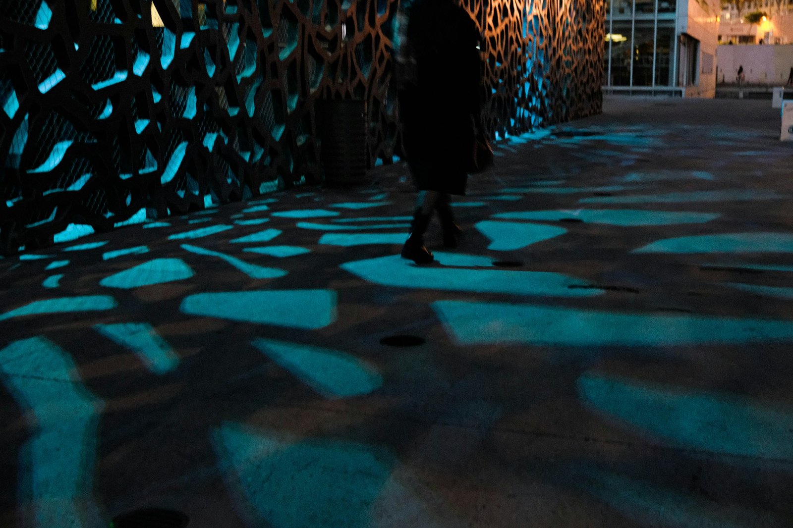 Personne marchant à travers des motifs lumineux bleus abstraits au sol — expérience immersive