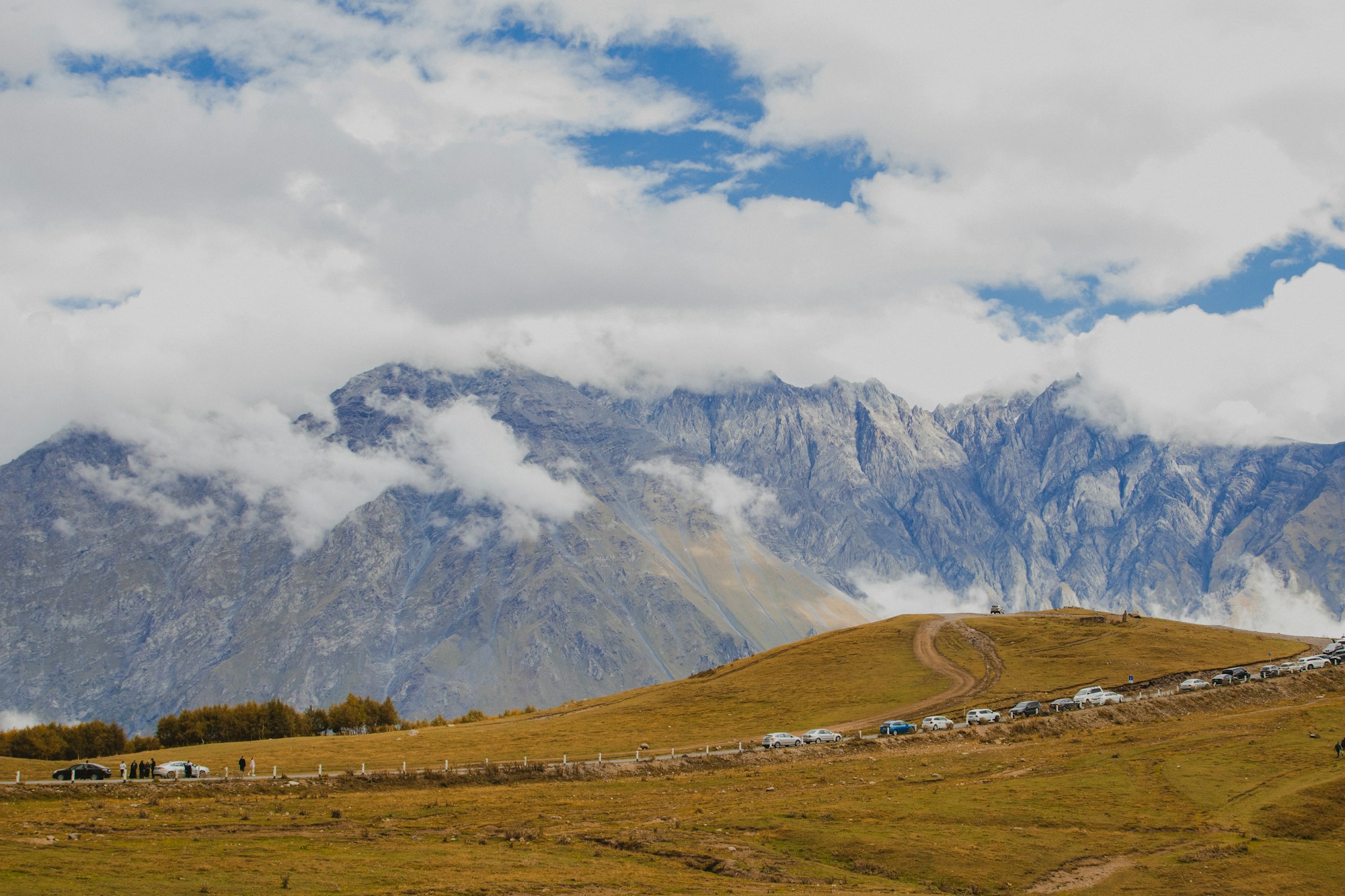La route militaire géorgienne serpentant à travers les montagnes majestueuses du Caucase avec l'église de la Trinité de Gergeti perchée sur son éperon rocheux