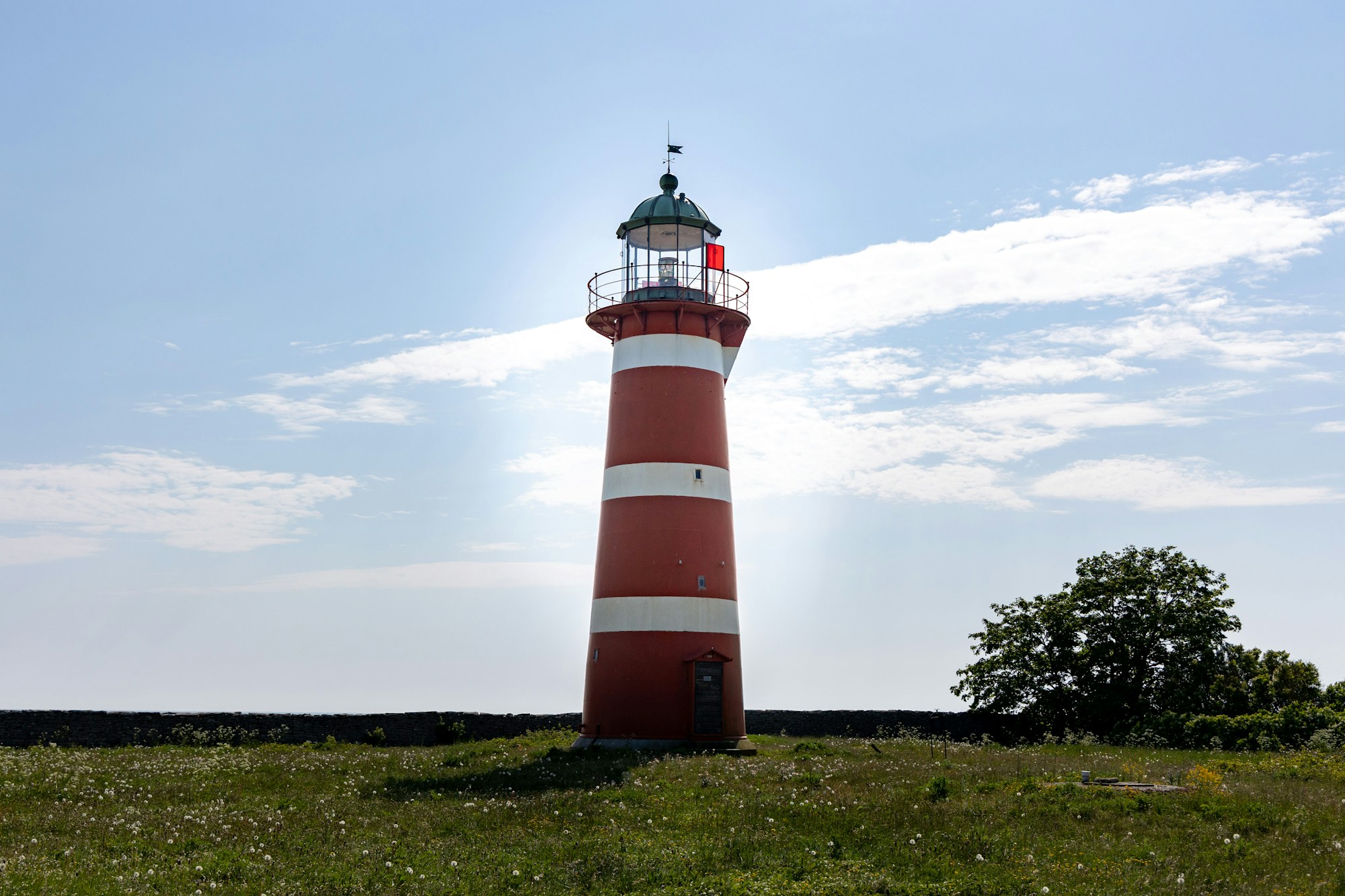 Phare rouge et blanc sur la côte verdoyante de Gotland, Suède — paysage baltique estival