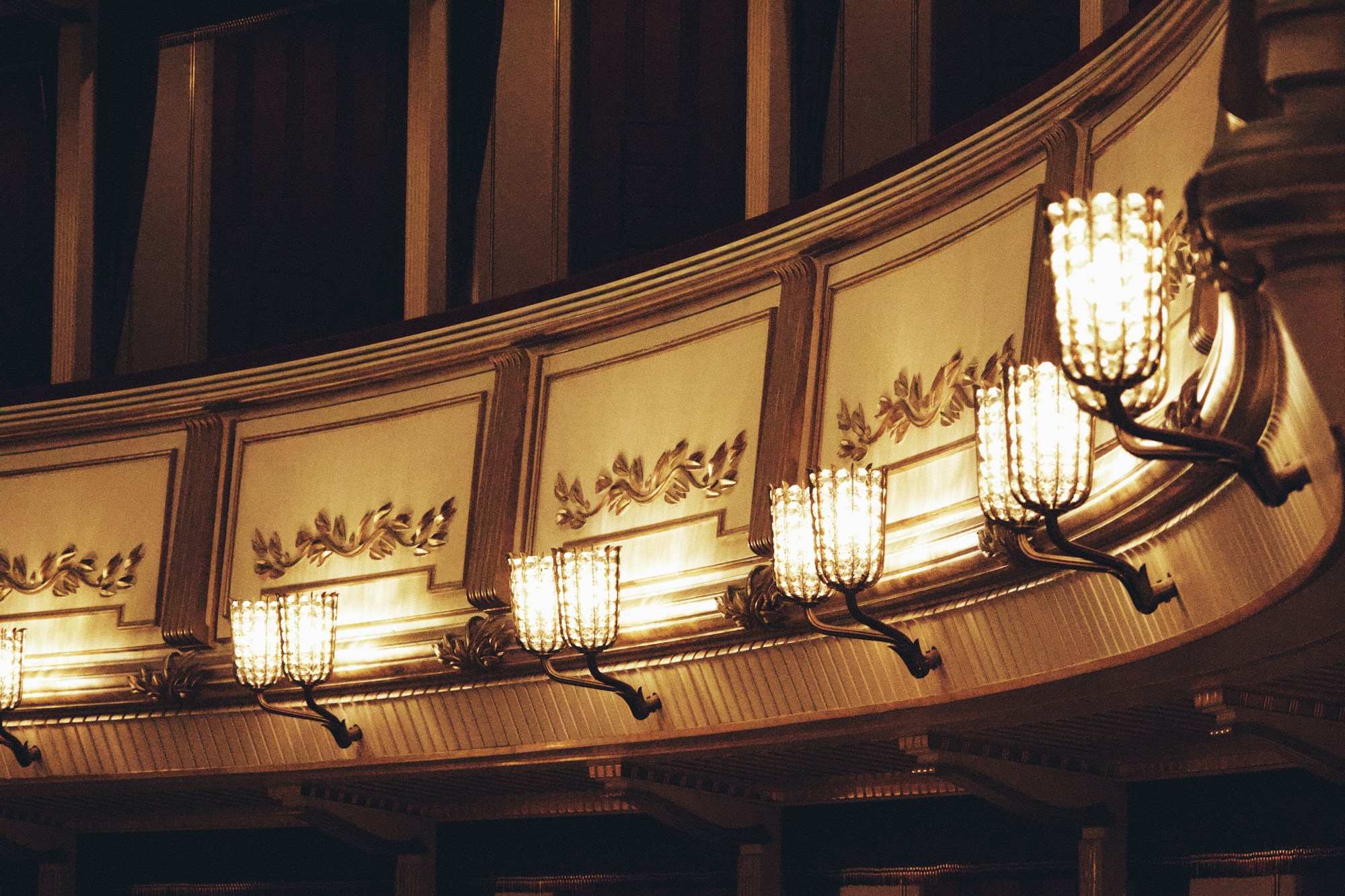 Interior of a baroque theatre with golden chandelier and red velvet seats