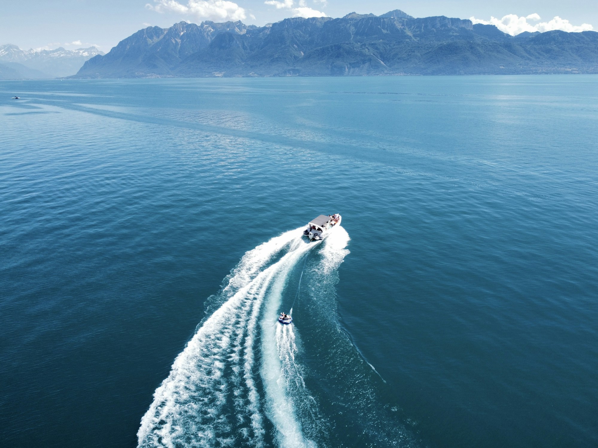 Boat sailing on Lake Geneva between France and Switzerland, surrounded by Alpine mountains