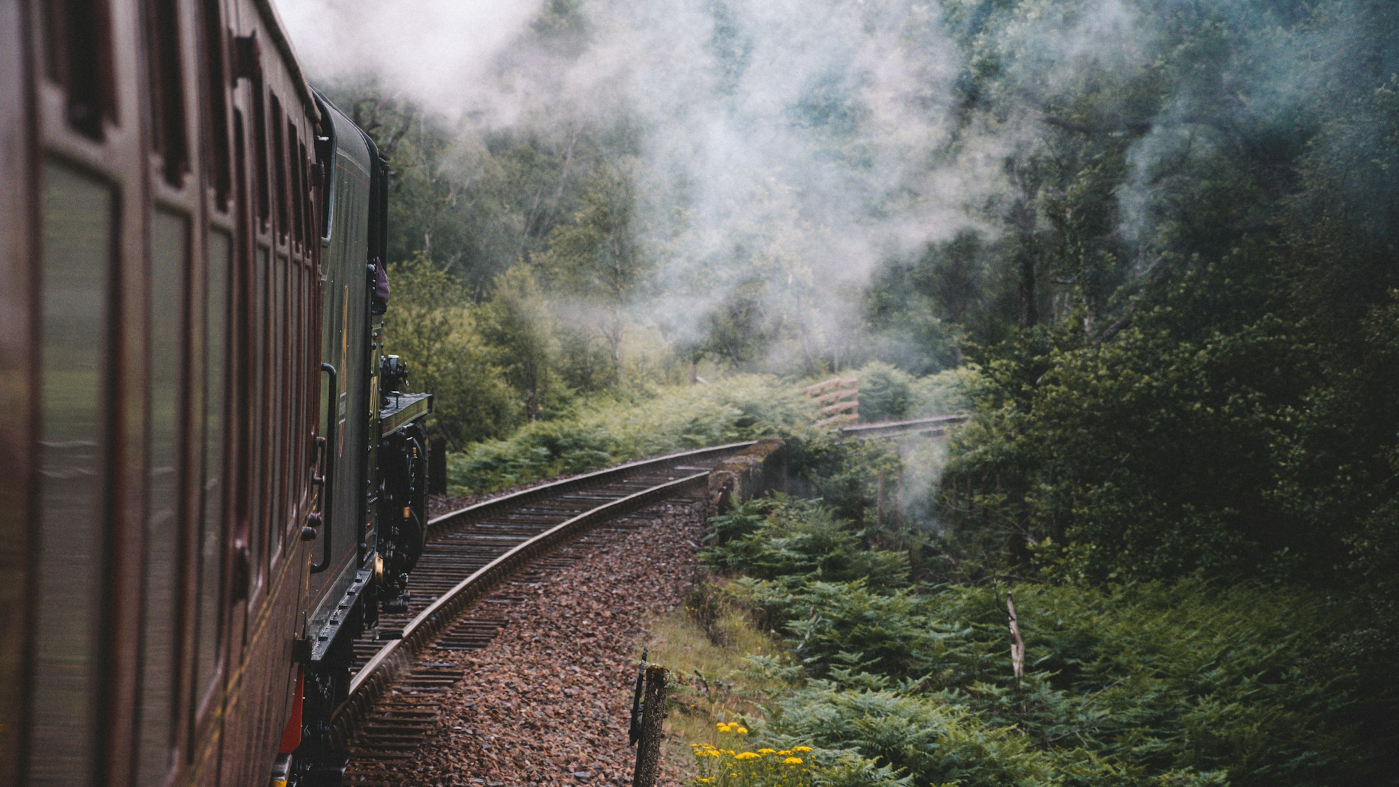The Jacobite train crossing the Glenfinnan Viaduct in Scotland with the Highlands in the background