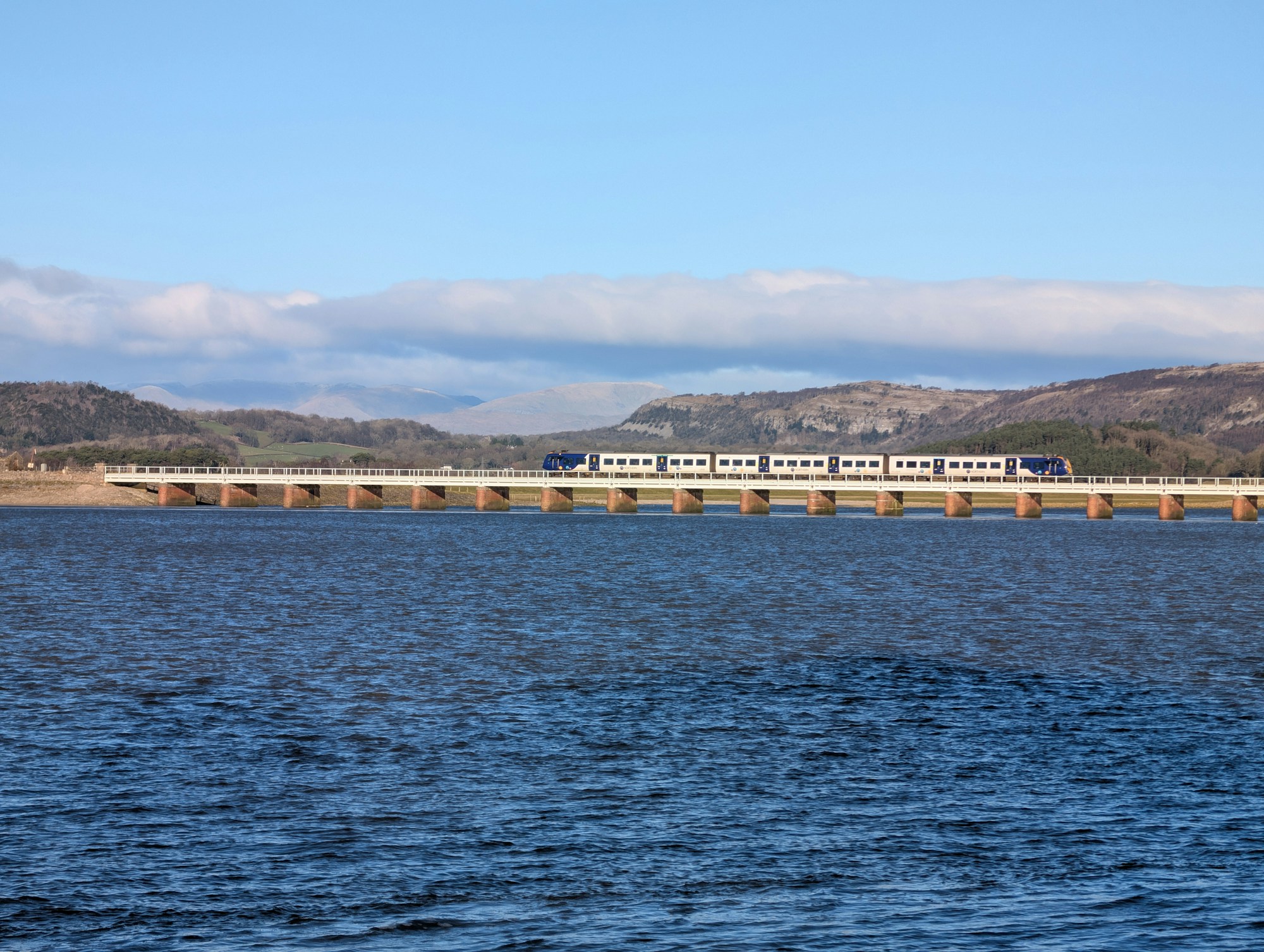 Train crossing a bridge over turquoise water in Europe