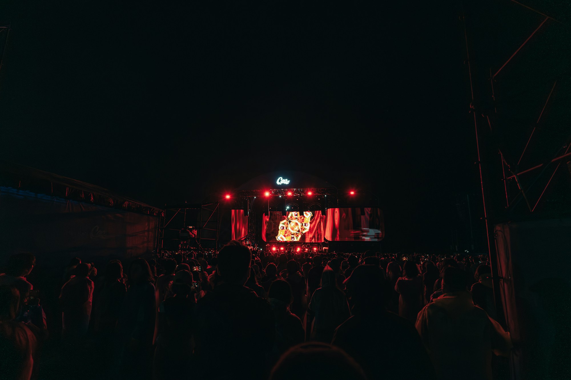 Foule de festivaliers devant une grande scène principale lors d'un concert en plein air nocturne