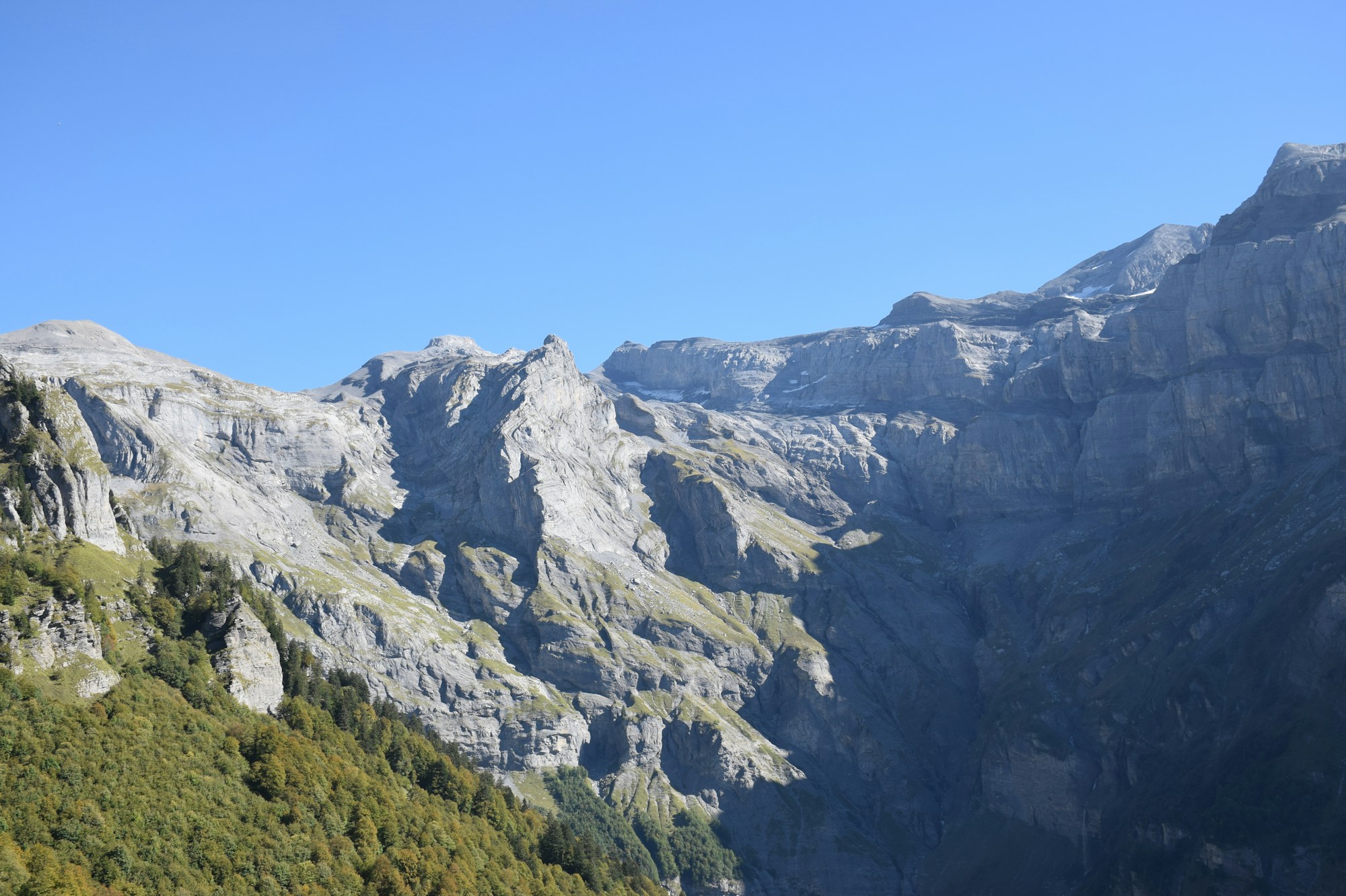 Massif alpin français sous un ciel bleu limpide, forêts et alpages caractéristiques des massifs du Jura et de la Franche-Comté