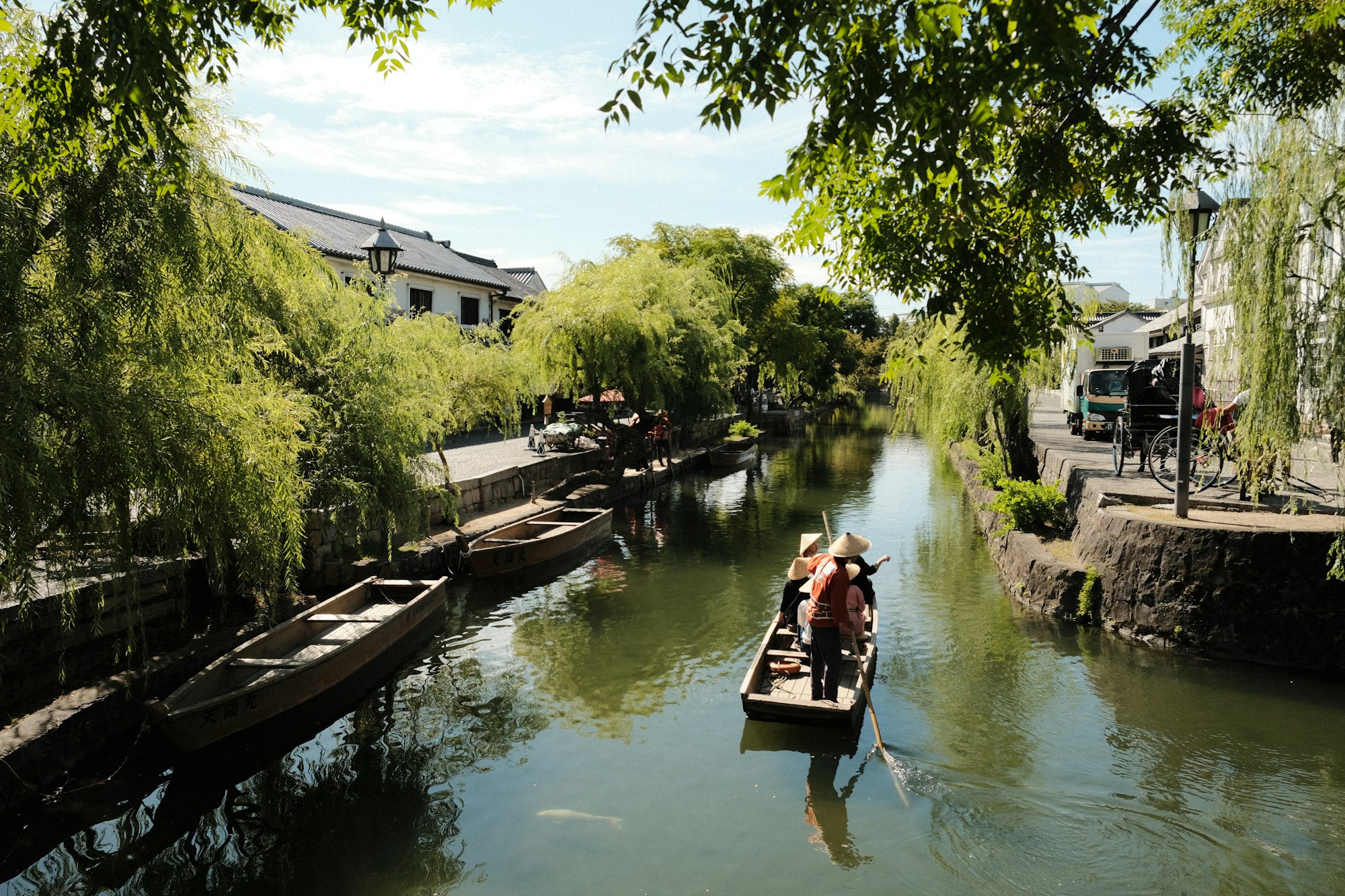 Barque traditionnelle sur un canal japonais aux eaux calmes bordé d'architecture historique