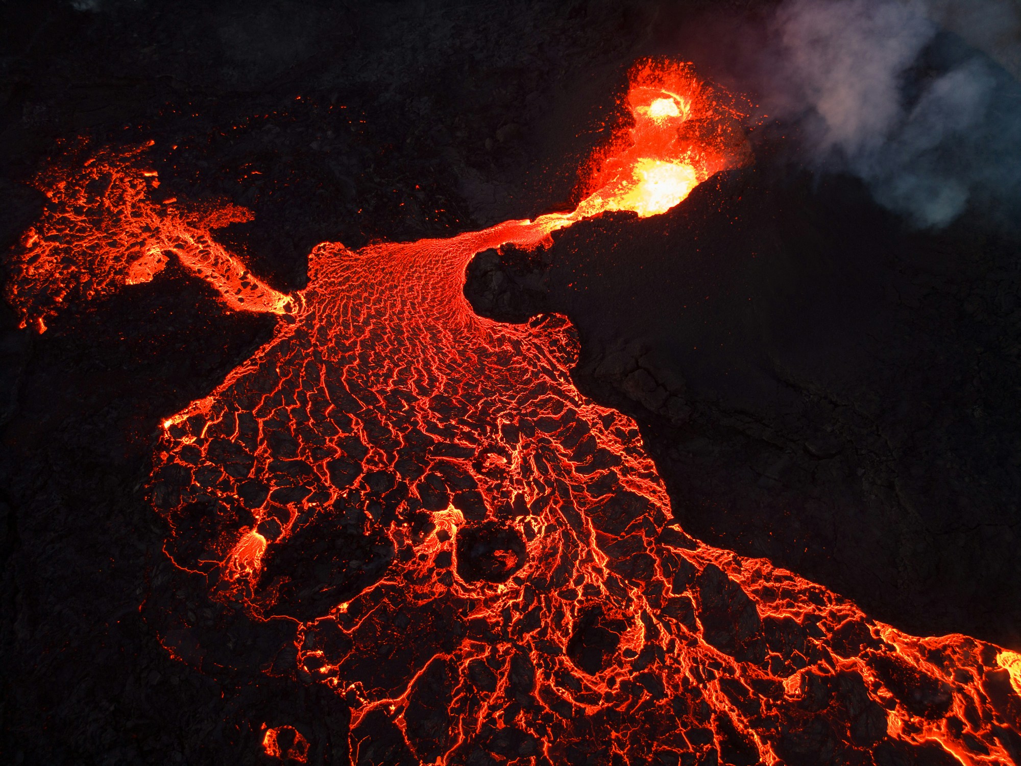 Aerial view of an active erupting volcano with glowing lava flows