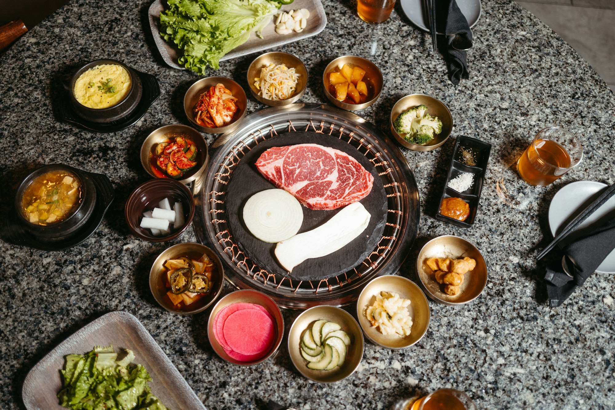 Mesa de barbacoa coreana con carne a la parrilla, verduras frescas y acompañamientos tradicionales