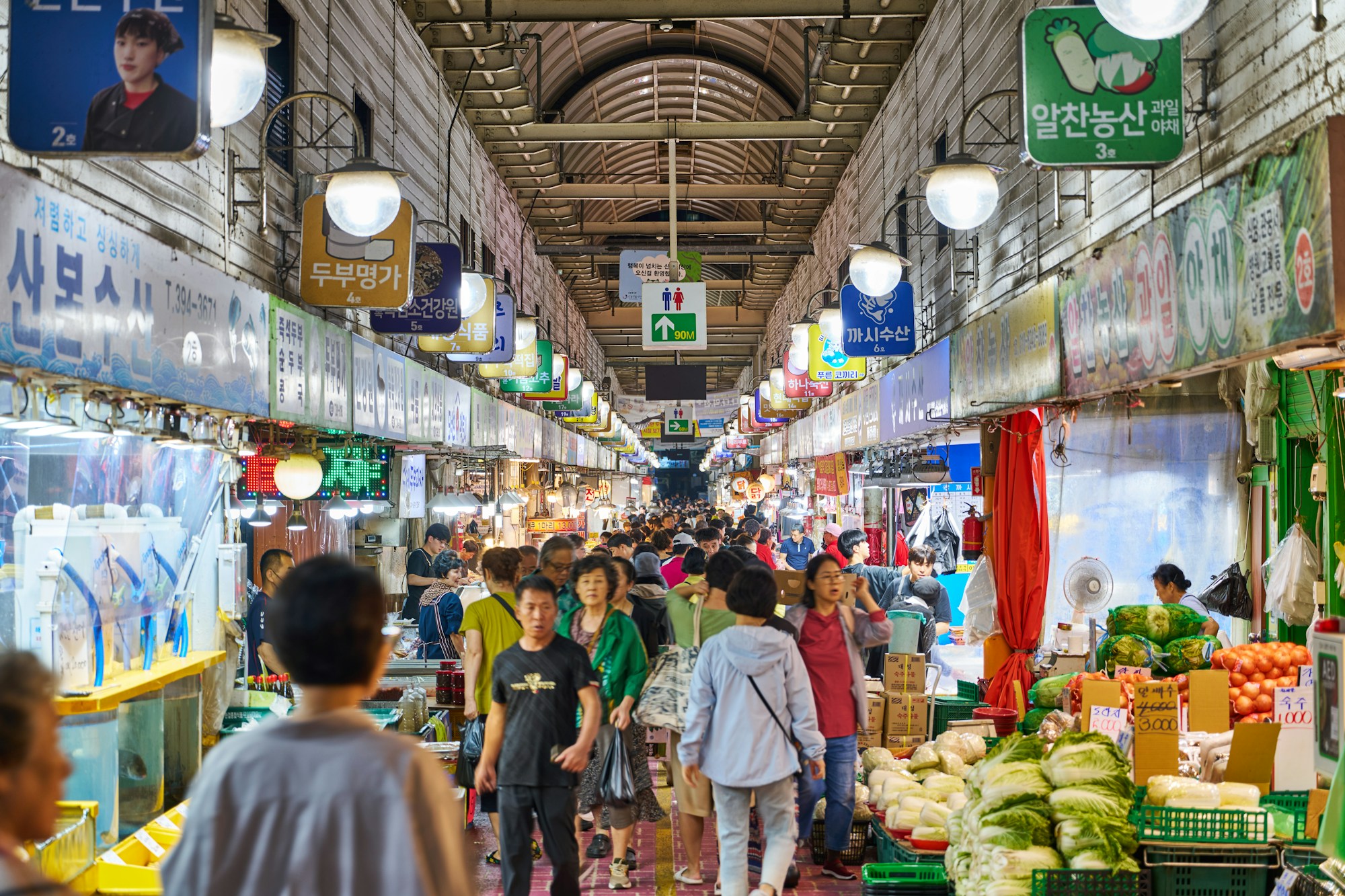 Animado mercado tradicional coreano con puestos de productos frescos y visitantes locales en Seúl
